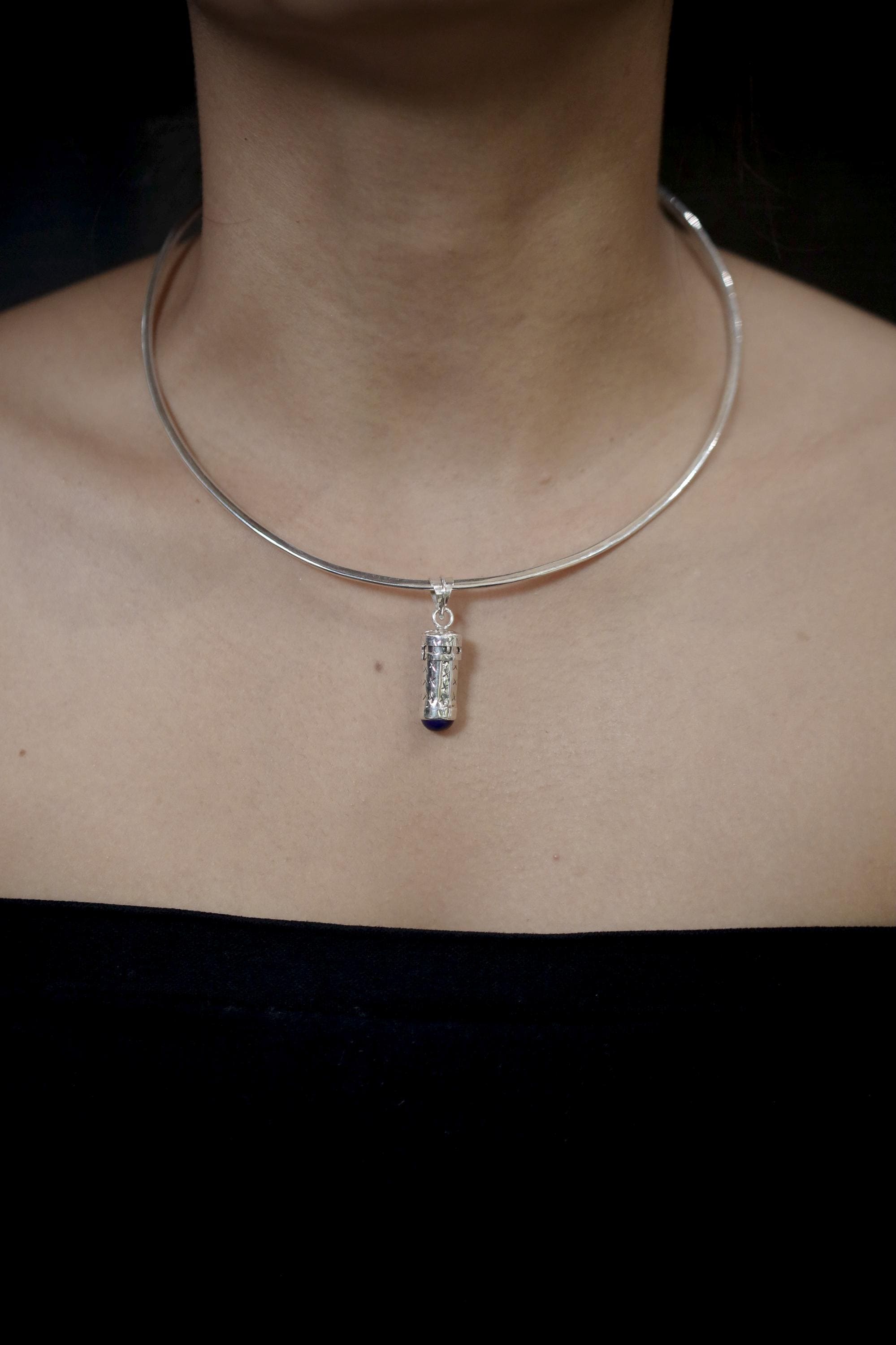 Lapis Lazuli capsule pendant displayed with chain on black background and polished silver body.