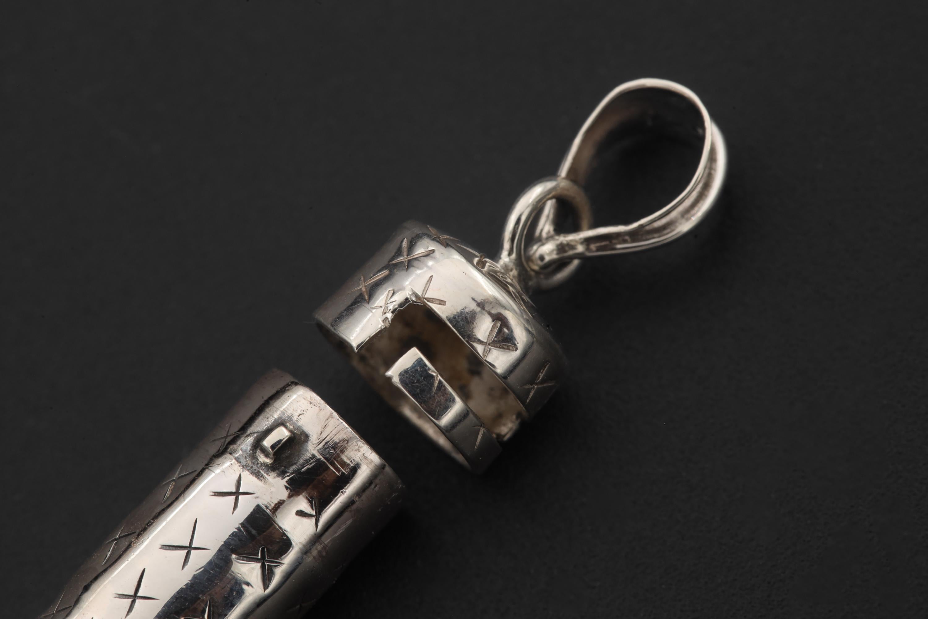 Polished sterling silver capsule pendant with Lapis Lazuli shown on sand and chain.