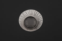 Sterling silver Sun magnifying glass pendant shown on dark background with central 5x optical lens.