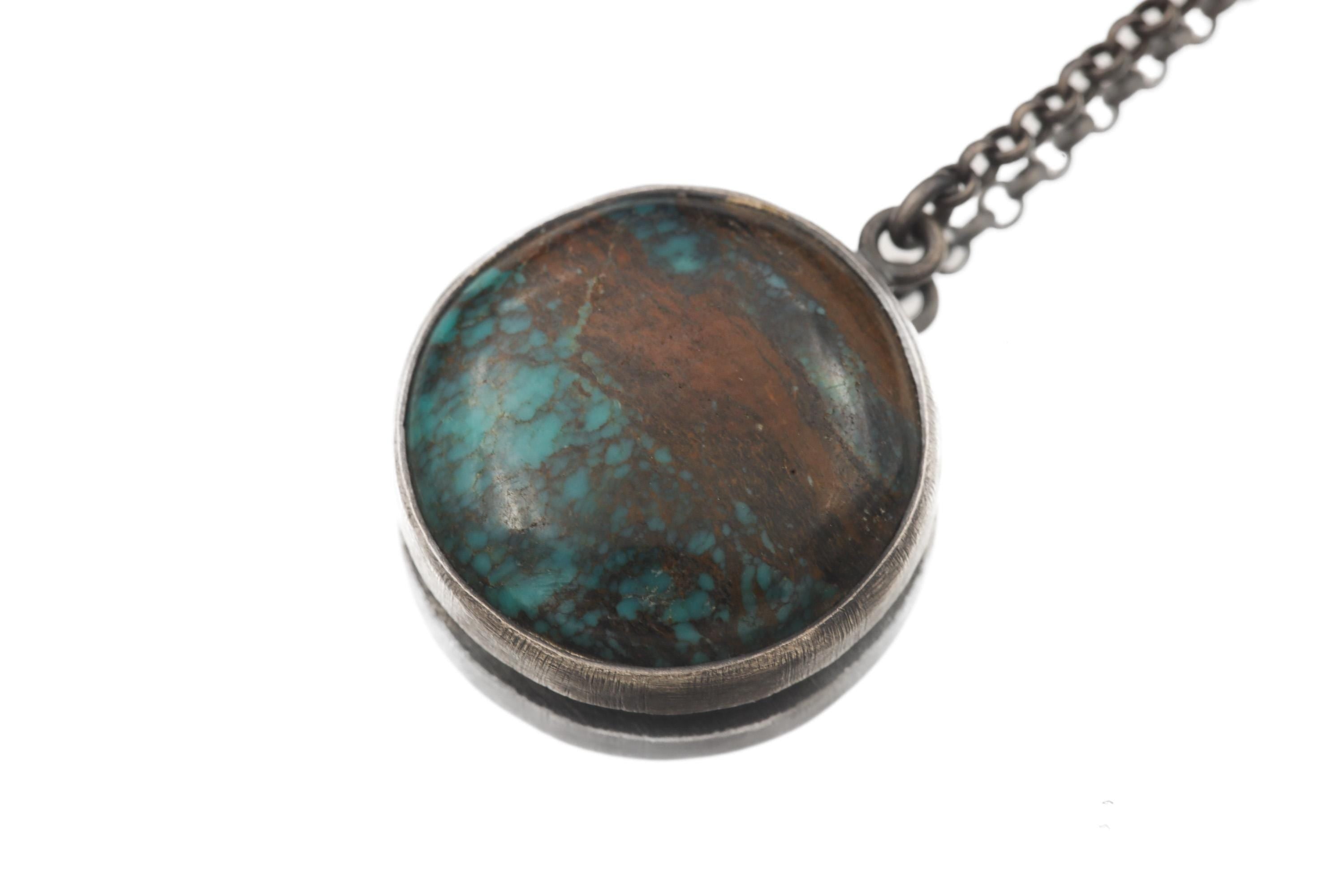 Close view of natural Turquoise cabochon pendant with blue-green colour and copper-brown matrix.