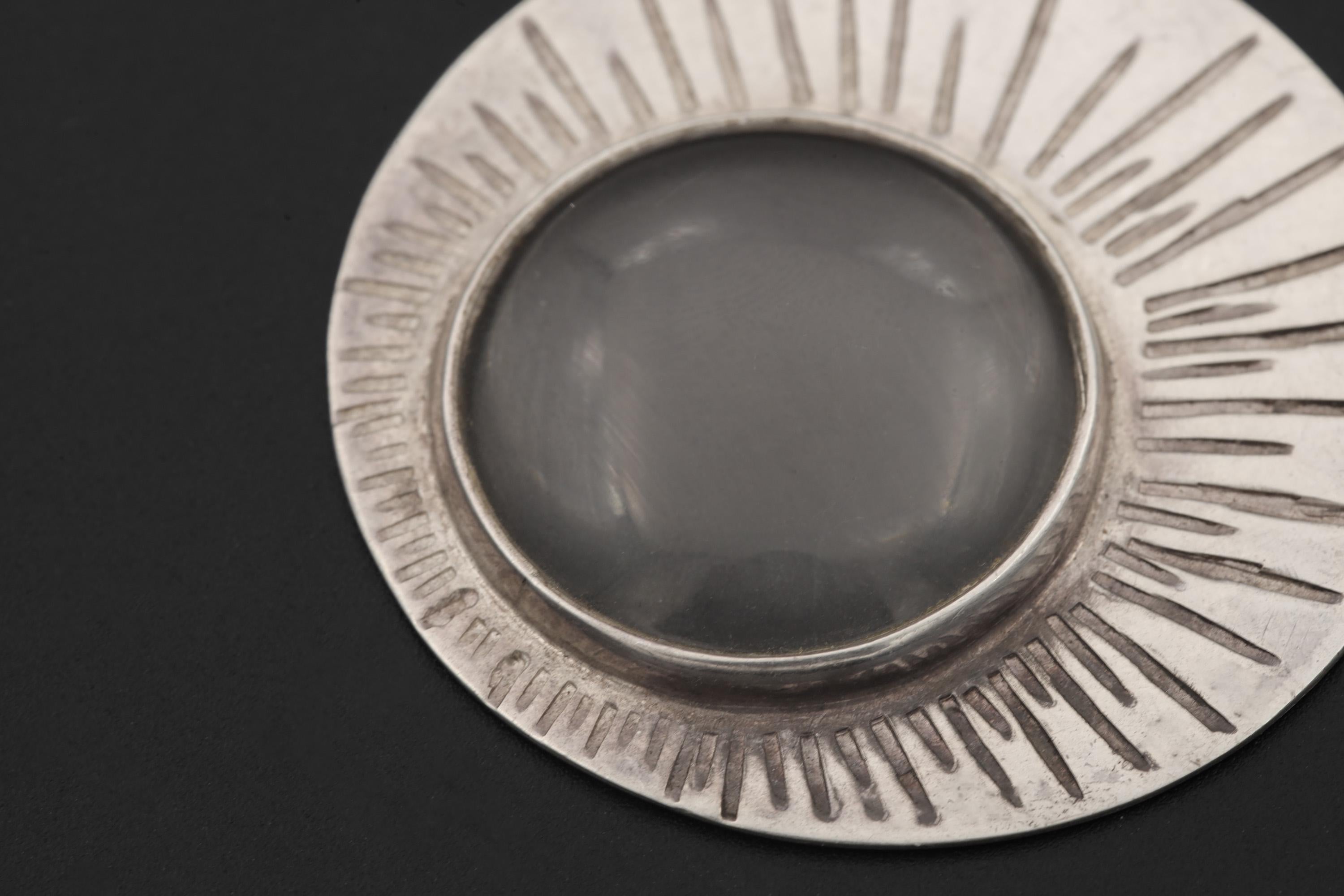 Detailed view of 5x optical magnifying glass pendant with oxidized sterling silver Sun ray texture.