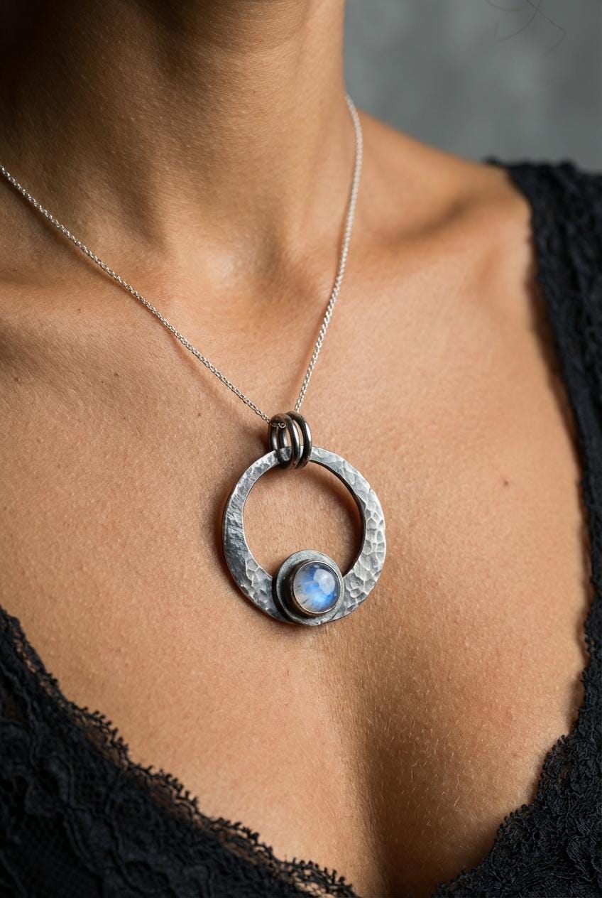 Blue Moonstone crescent pendant shown worn on a model, with oxidized sterling silver moon frame and luminous round stone.