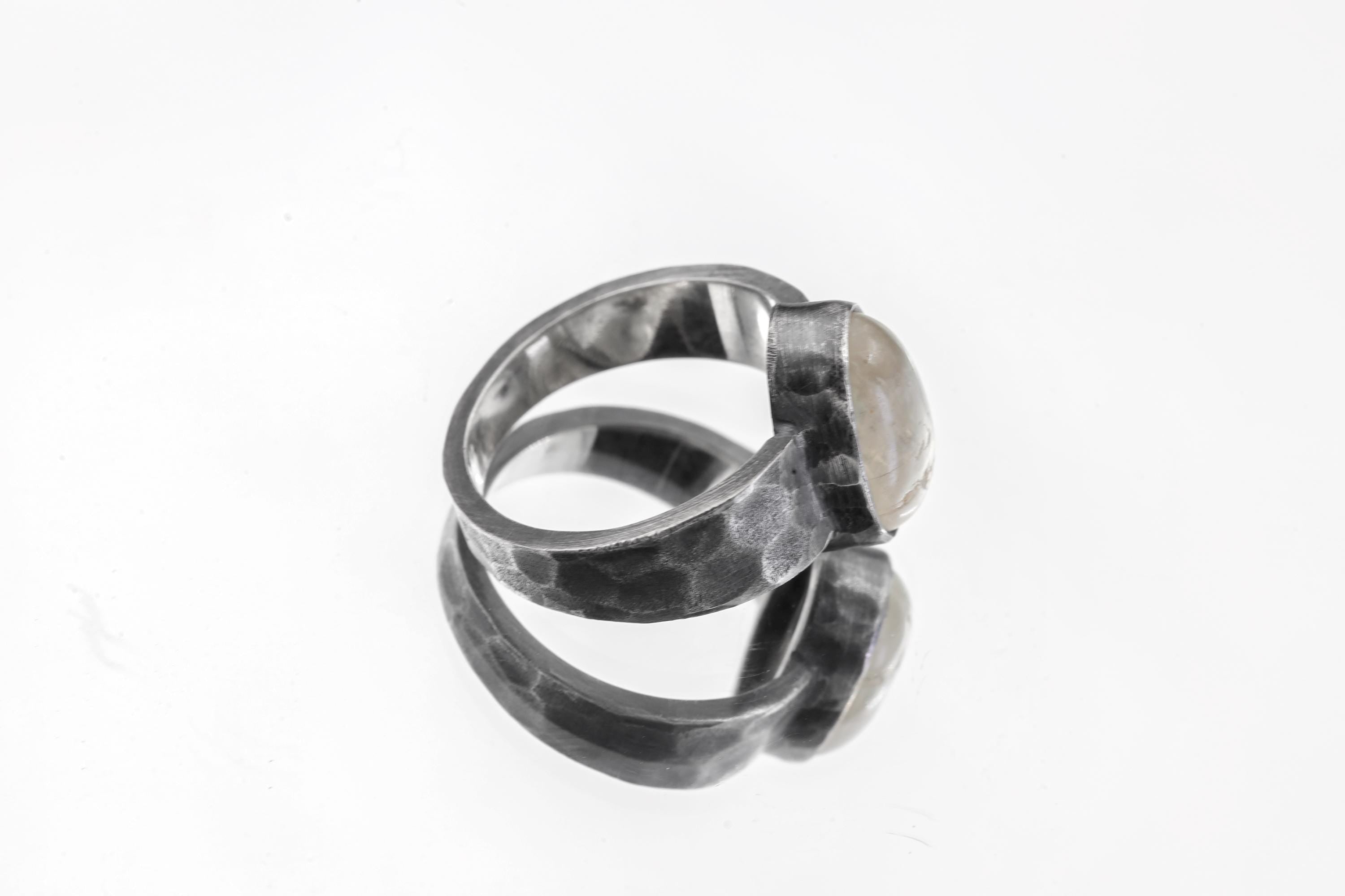 Side view of Blue Moonstone men’s ring showing wide hammered oxidized sterling silver band and raised bezel setting.