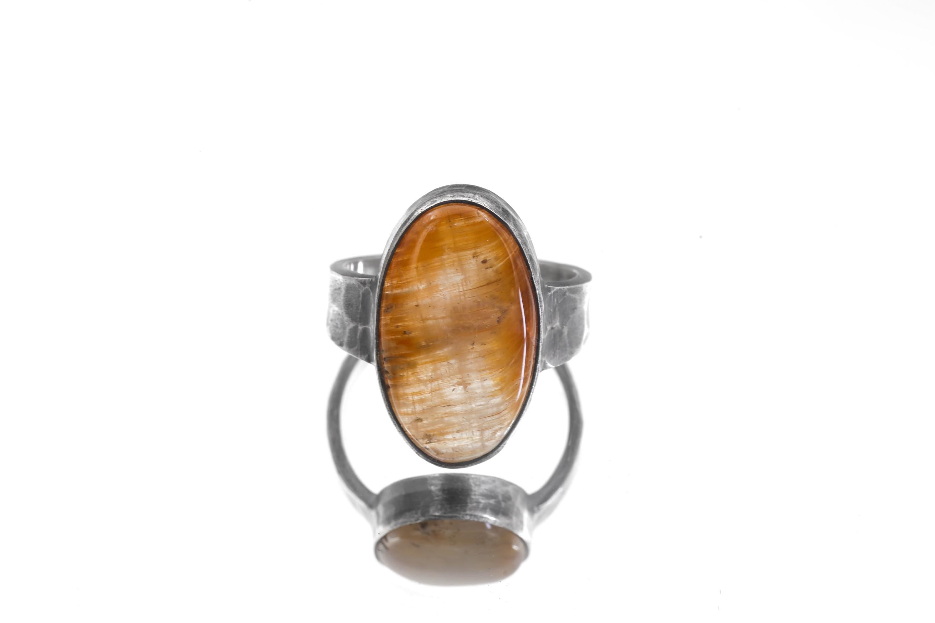 Gold Rutilated Quartz ring displayed on cracked earth with strong silver band and warm golden stone.