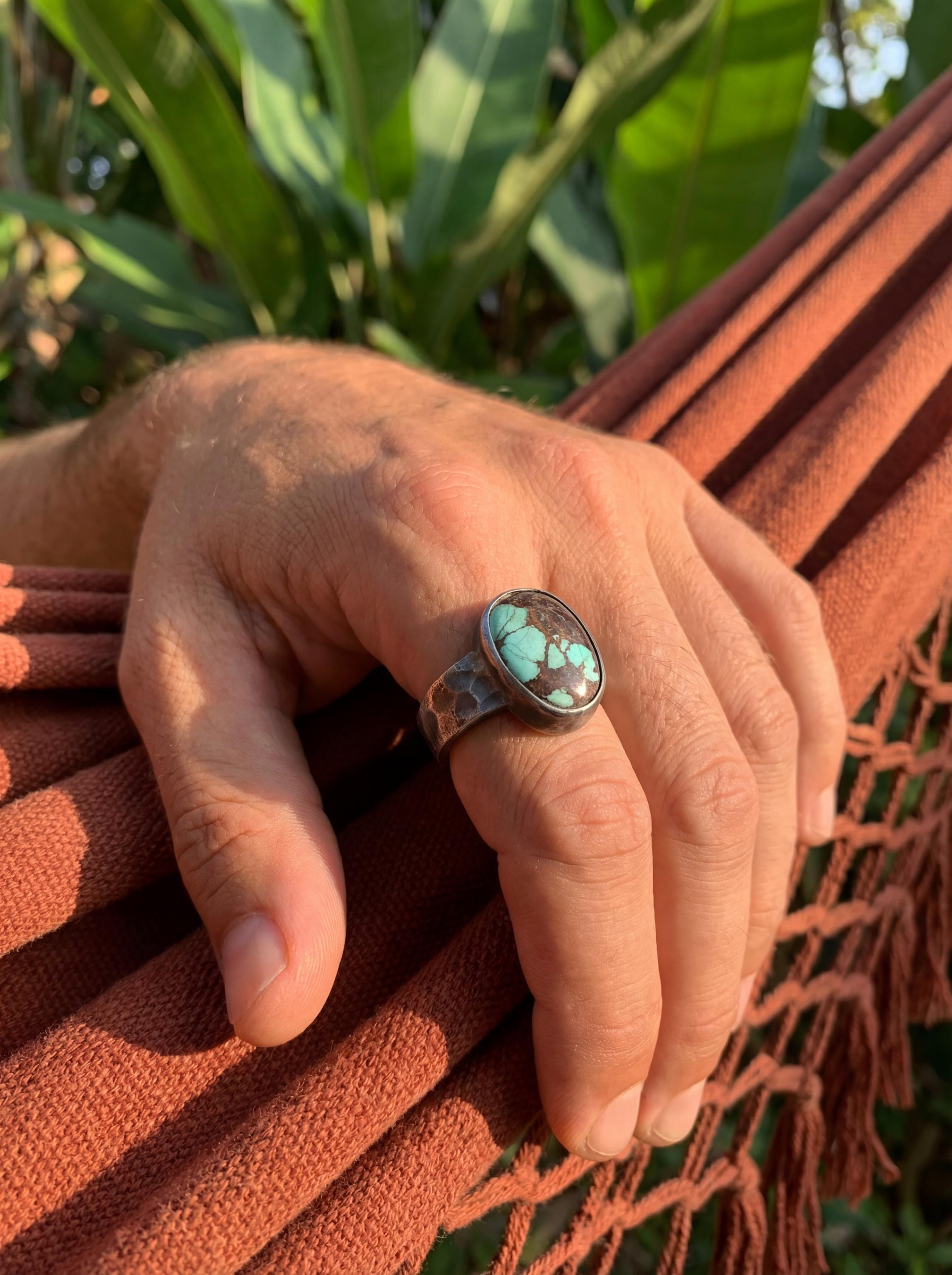Tibetan Turquoise ring shown worn outdoors, with green-blue matrix stone and rugged handmade silver setting.