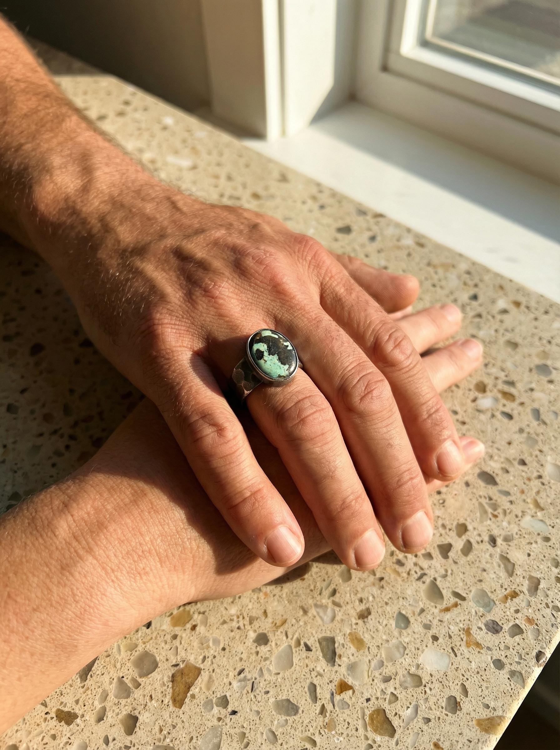 Tibetan Turquoise men’s ring shown worn on the hand, highlighting the oval green trade bead cabochon and wide silver band.