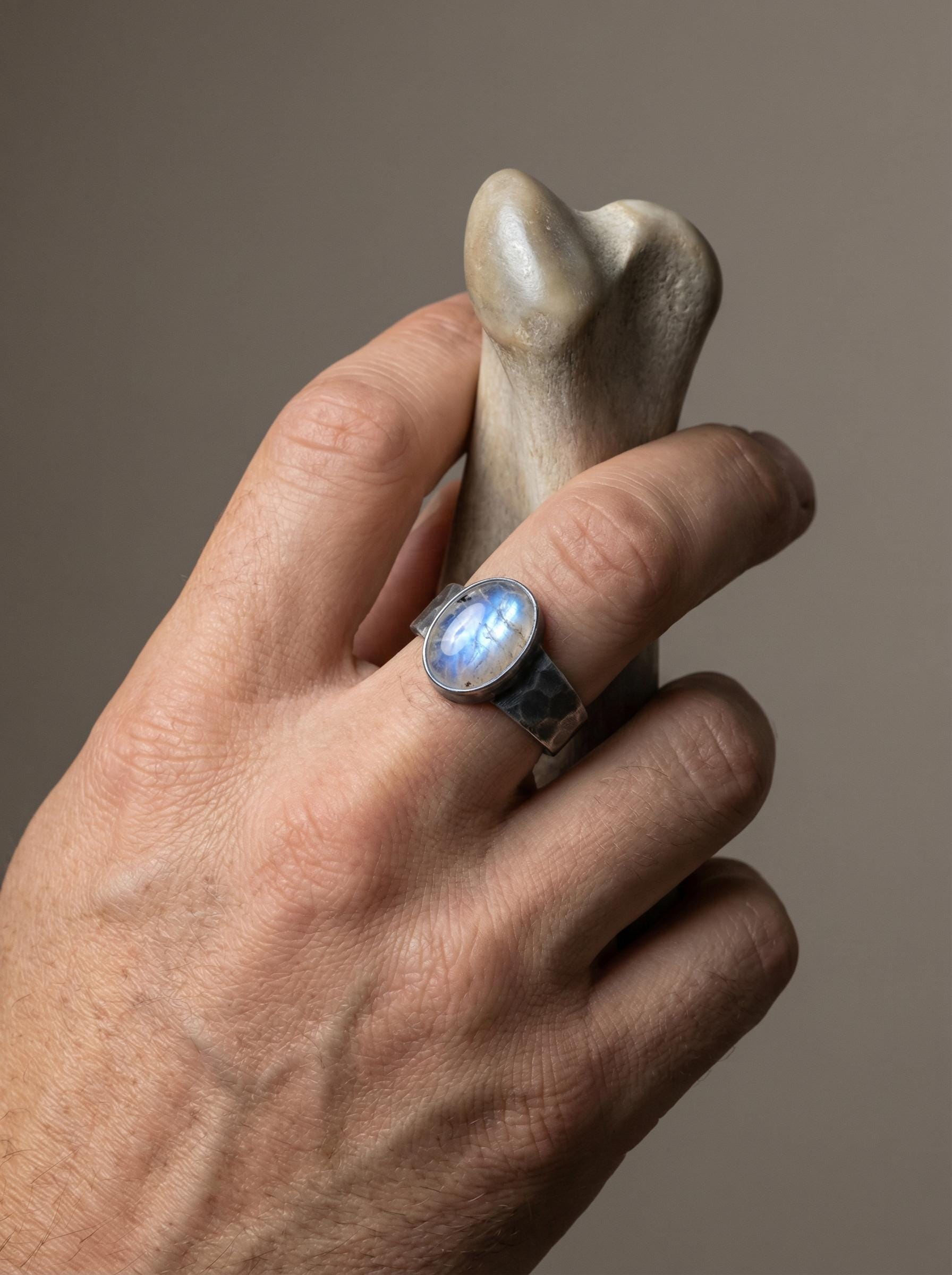 AAA Blue Moonstone oxidized silver ring shown worn on the hand, highlighting the pale blue adularescence and sturdy band.
