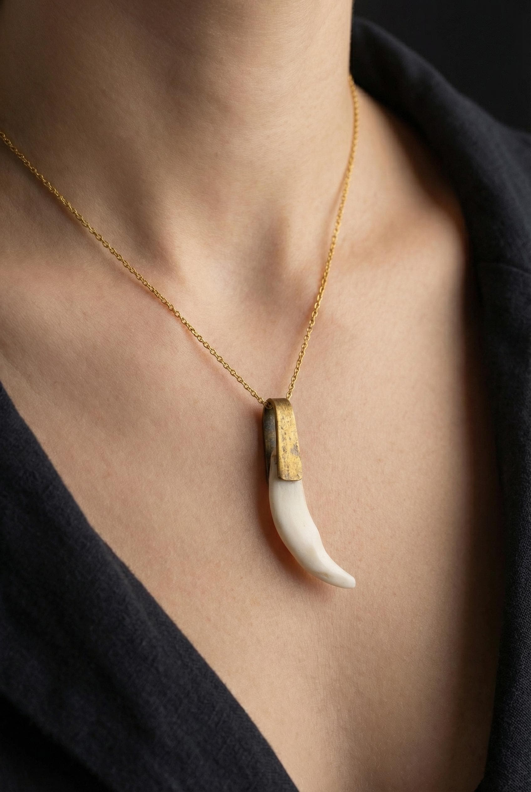 Antique tooth pendant shown worn on a necklace, with gold-plated brass pivoting bail and curved white found-object charm.