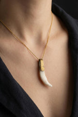 Antique tooth pendant shown worn on a necklace, with gold-plated brass pivoting bail and curved white found-object charm.