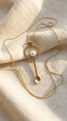 South Sea Pearl fairy spoon pendant displayed on soft fabric with gold chain and polished brass spoon form.