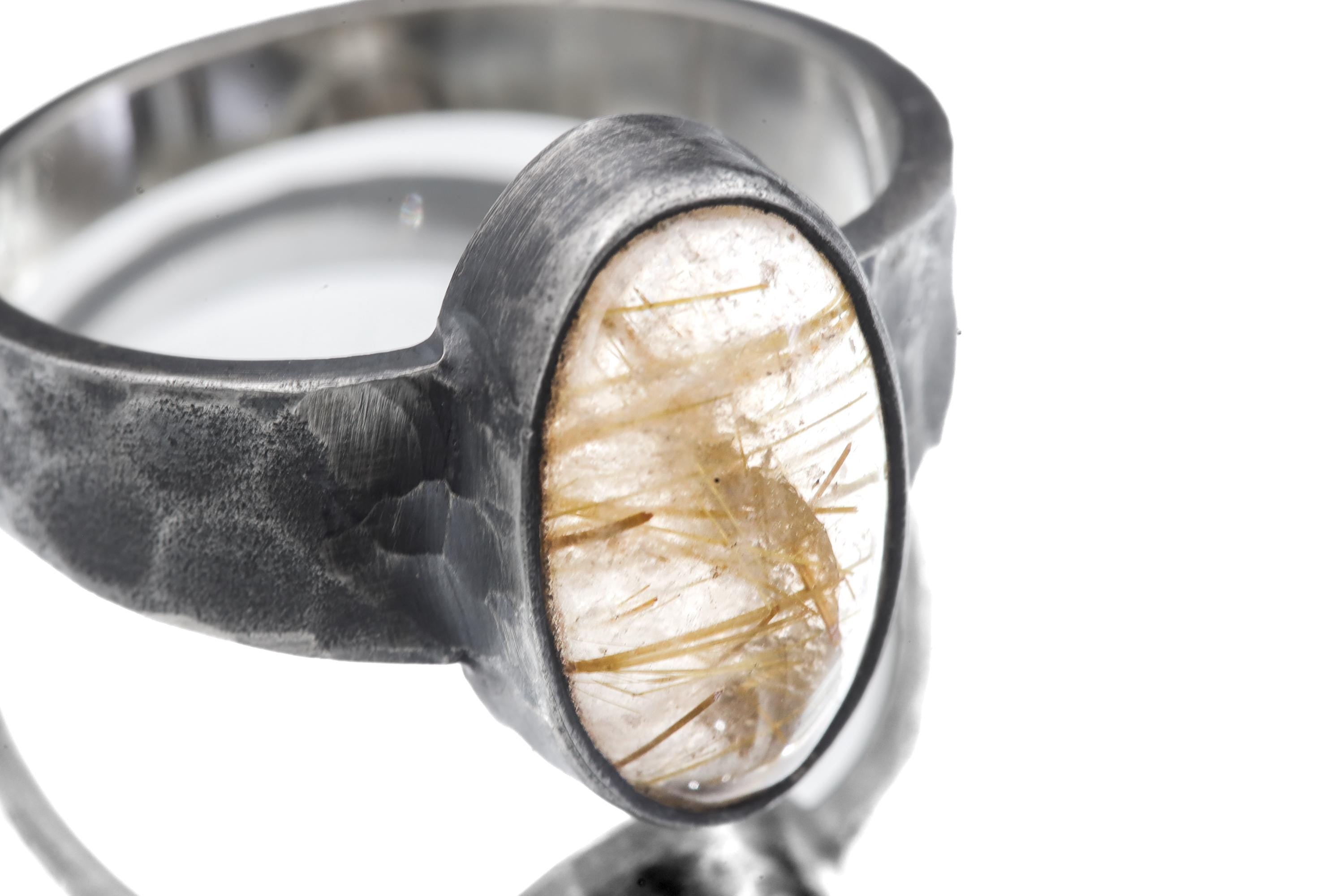 Close-up of Gold Rutilated Clear Quartz oval cabochon ring showing golden rutile needles and oxidized silver bezel.