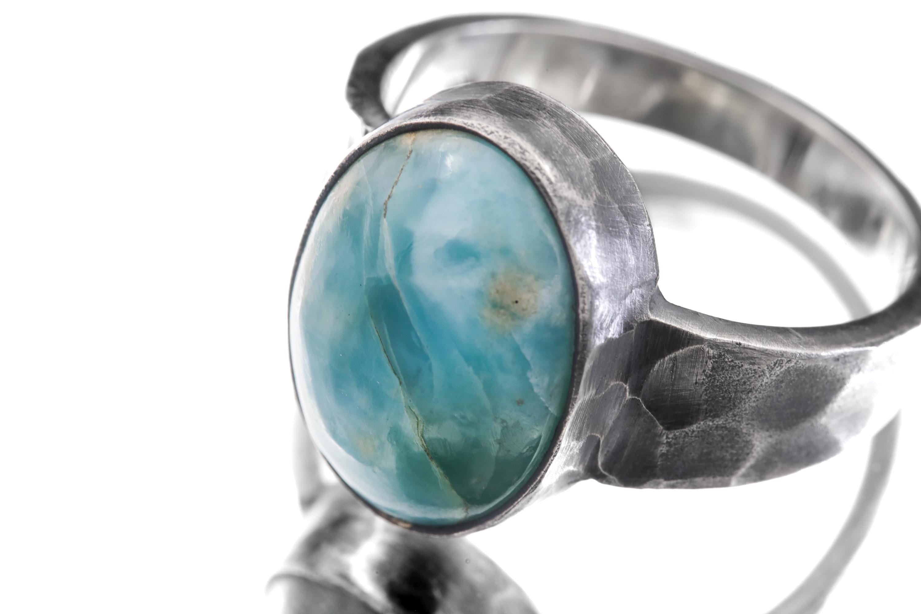 Close-up of AAA Larimar men’s ring showing oval blue pectolite cabochon, deep bezel, and hammered silver texture.