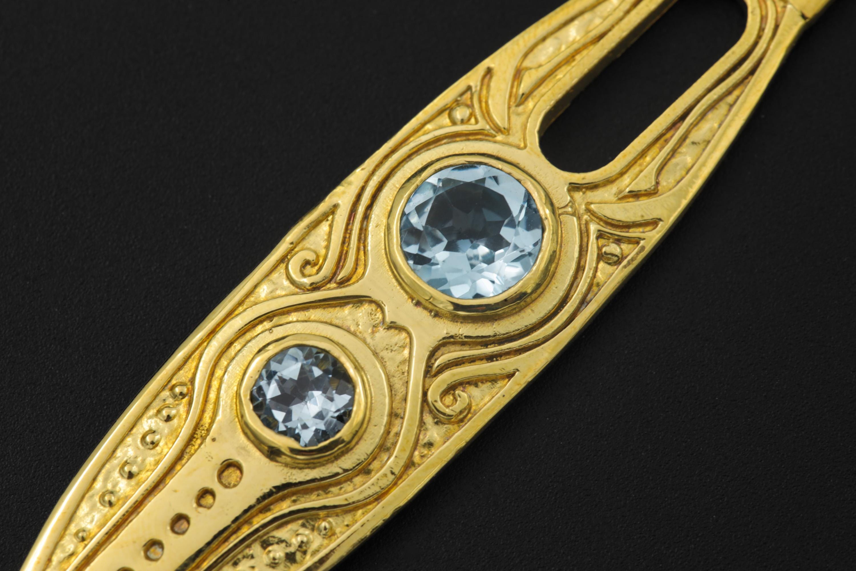 Close-up of Blue Topaz Spoon Pendant showing ornamental carved brass detail and round blue gemstone settings.