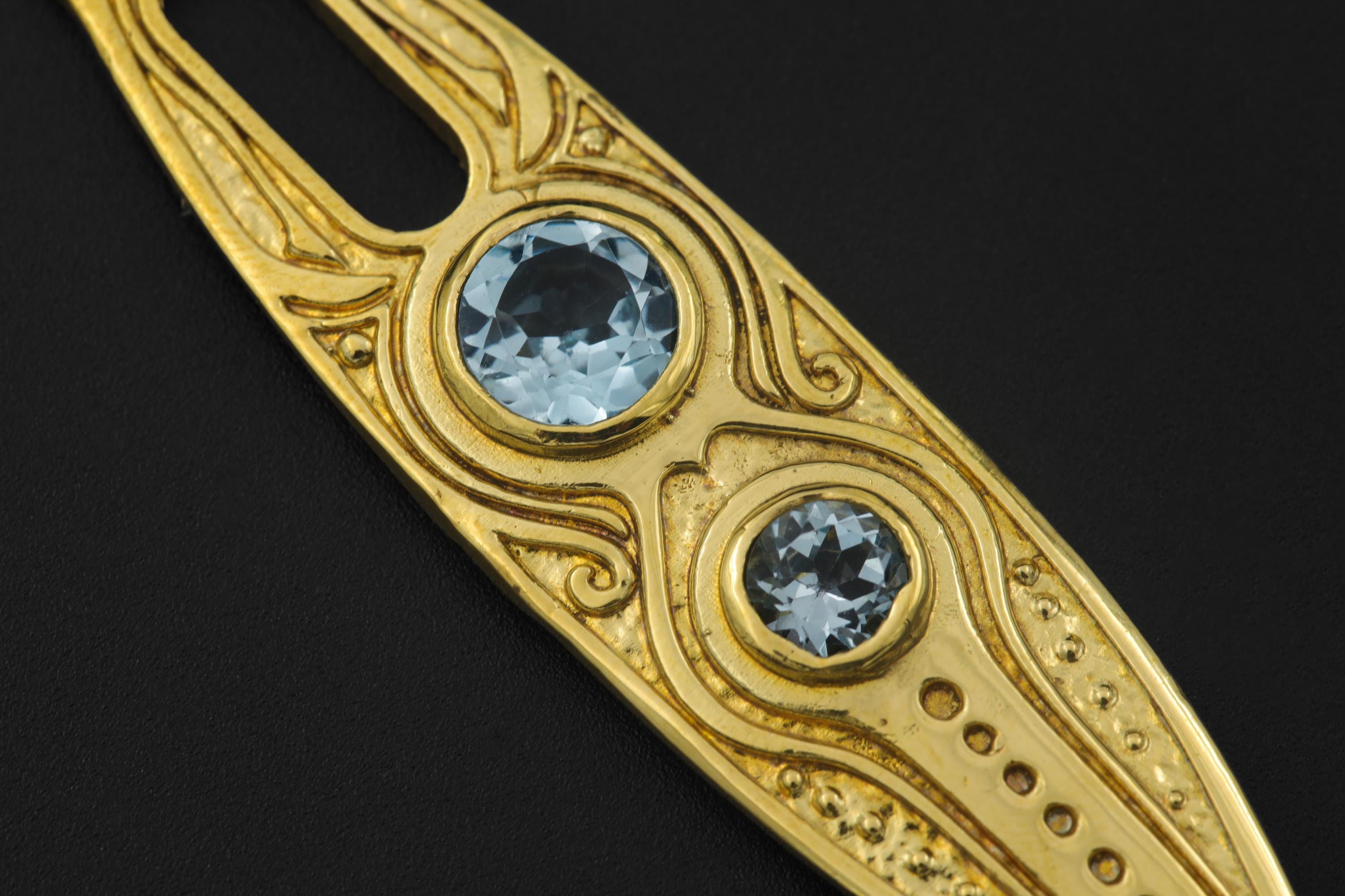 Close-up of Blue Topaz Spoon Pendant showing ornamental carved brass detail and round blue gemstone settings.