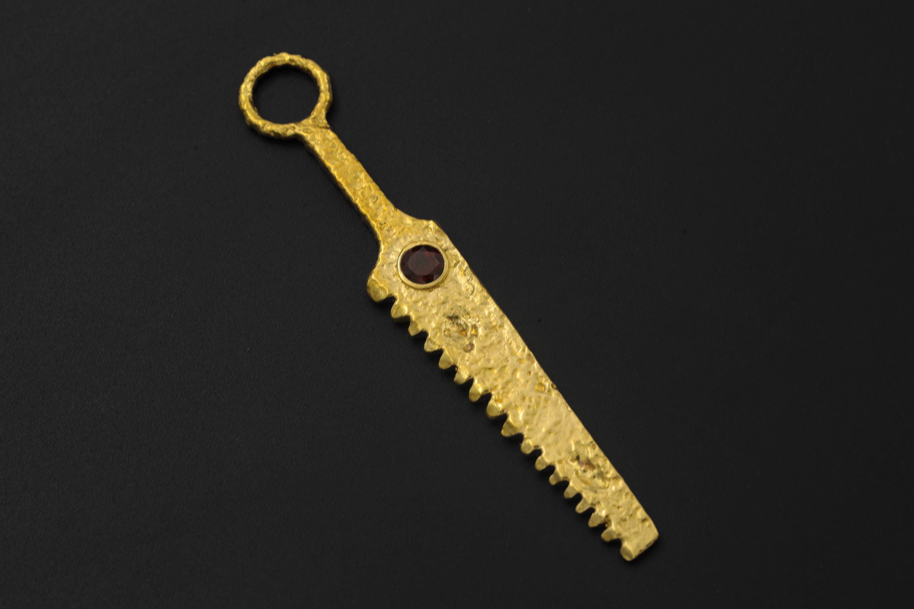 Close view of serrated gold-plated brass cutter spoon pendant with textured handmade surface.