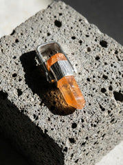Australian Lemurian Quartz point pendant on black background with hammered sterling silver cap and warm orange crystal body.