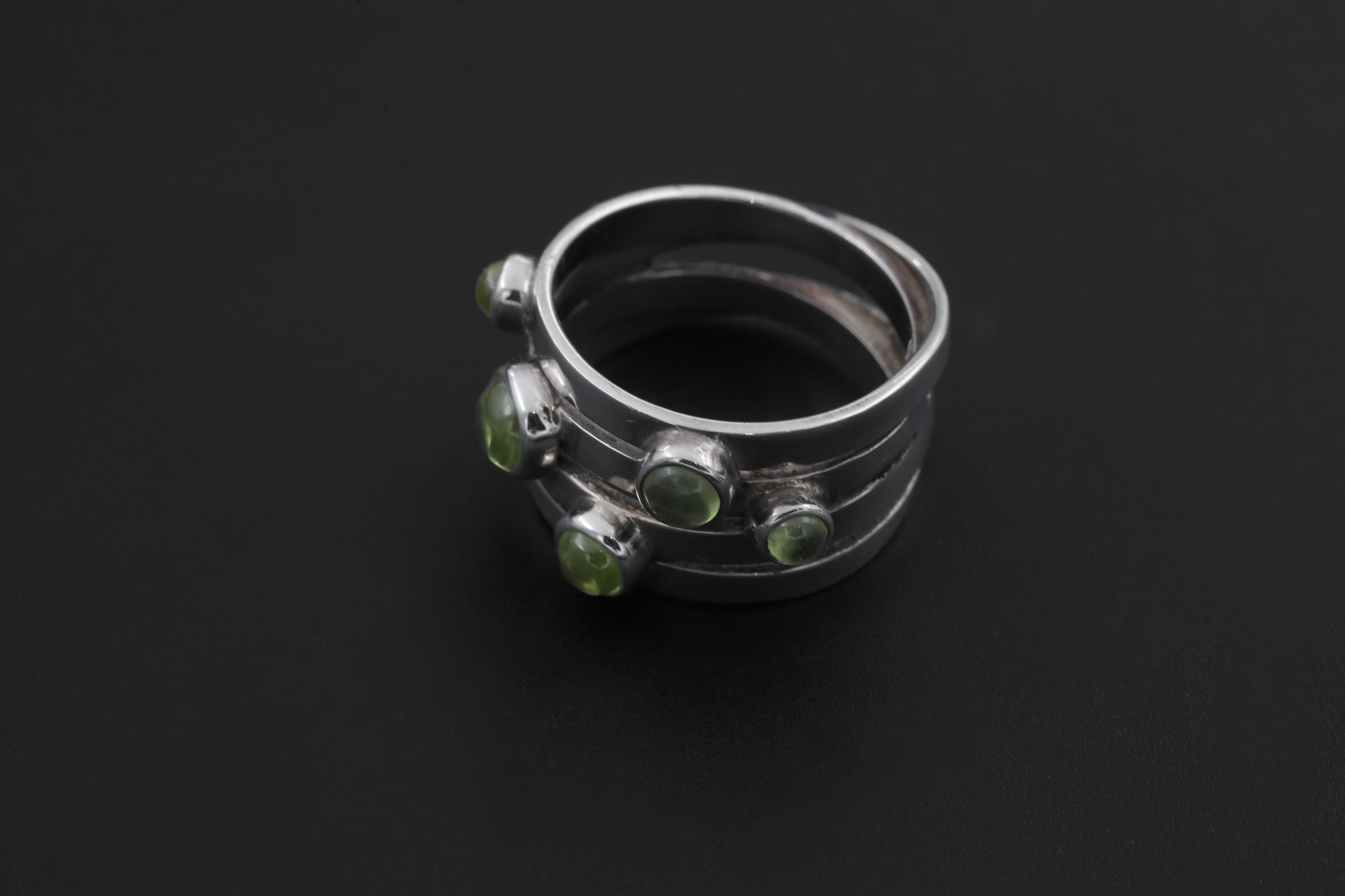 Five Stone Peridot Ring displayed on dark background with polished silver bezel settings.
