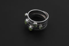 Five Stone Peridot Ring displayed on dark background with polished silver bezel settings.