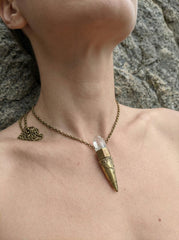 Clear Quartz torch pendant shown worn on model with brass setting and crystal point.