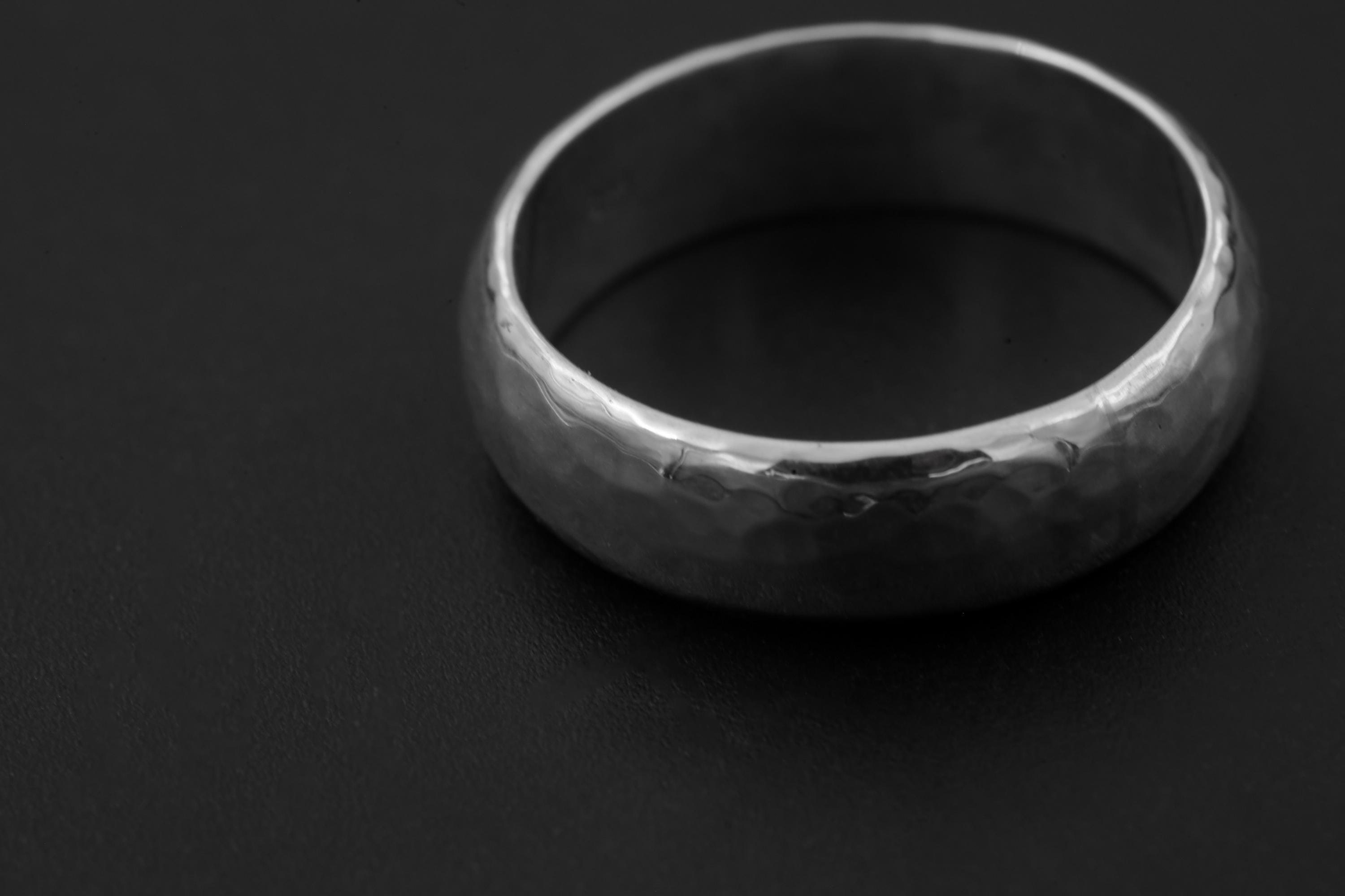 Close view of solid sterling silver band showing softly faceted hammered surface.