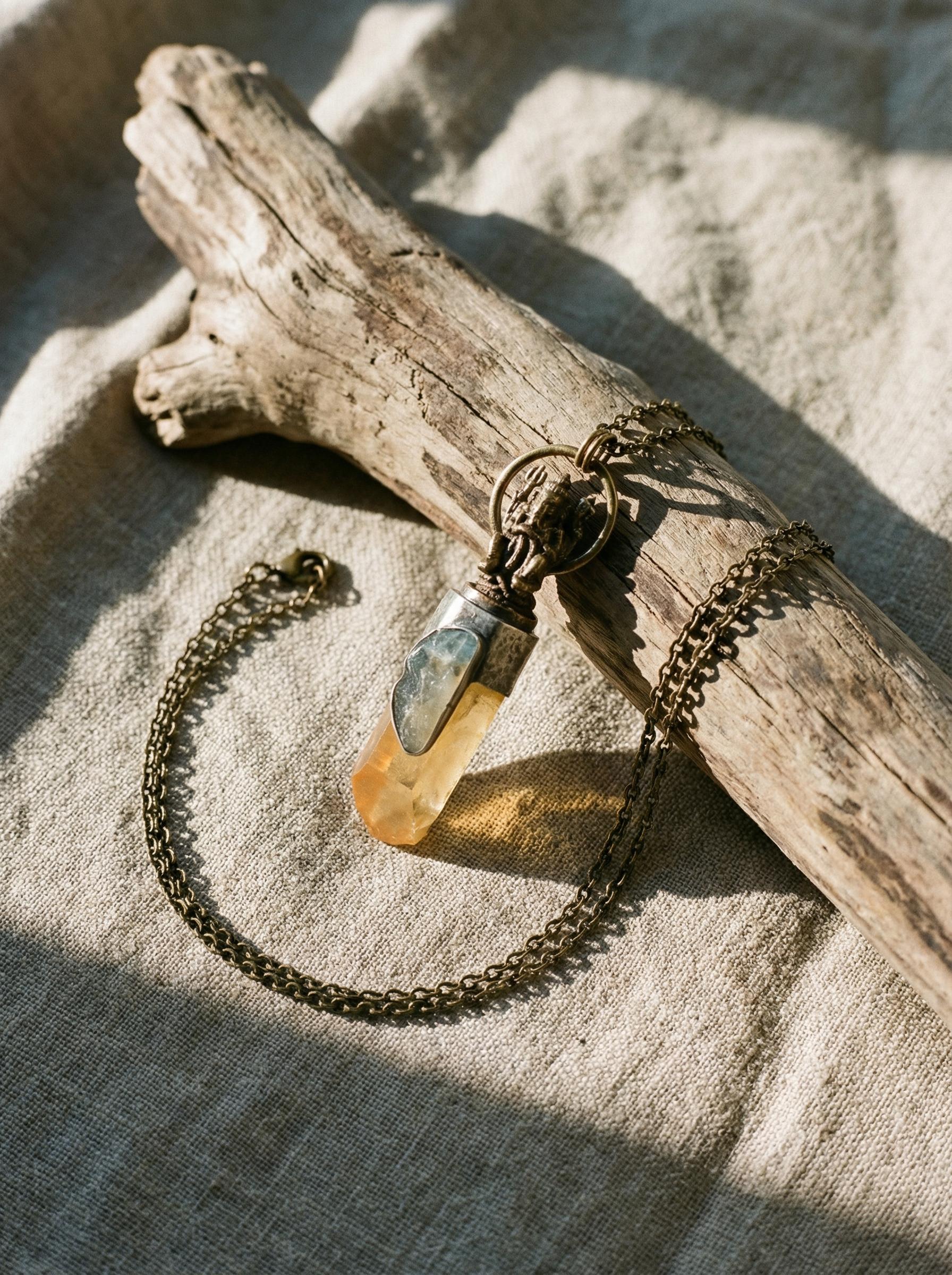 Ganesha Quartz pendant displayed on driftwood with golden Lemurian point and Aquamarine accent stone.