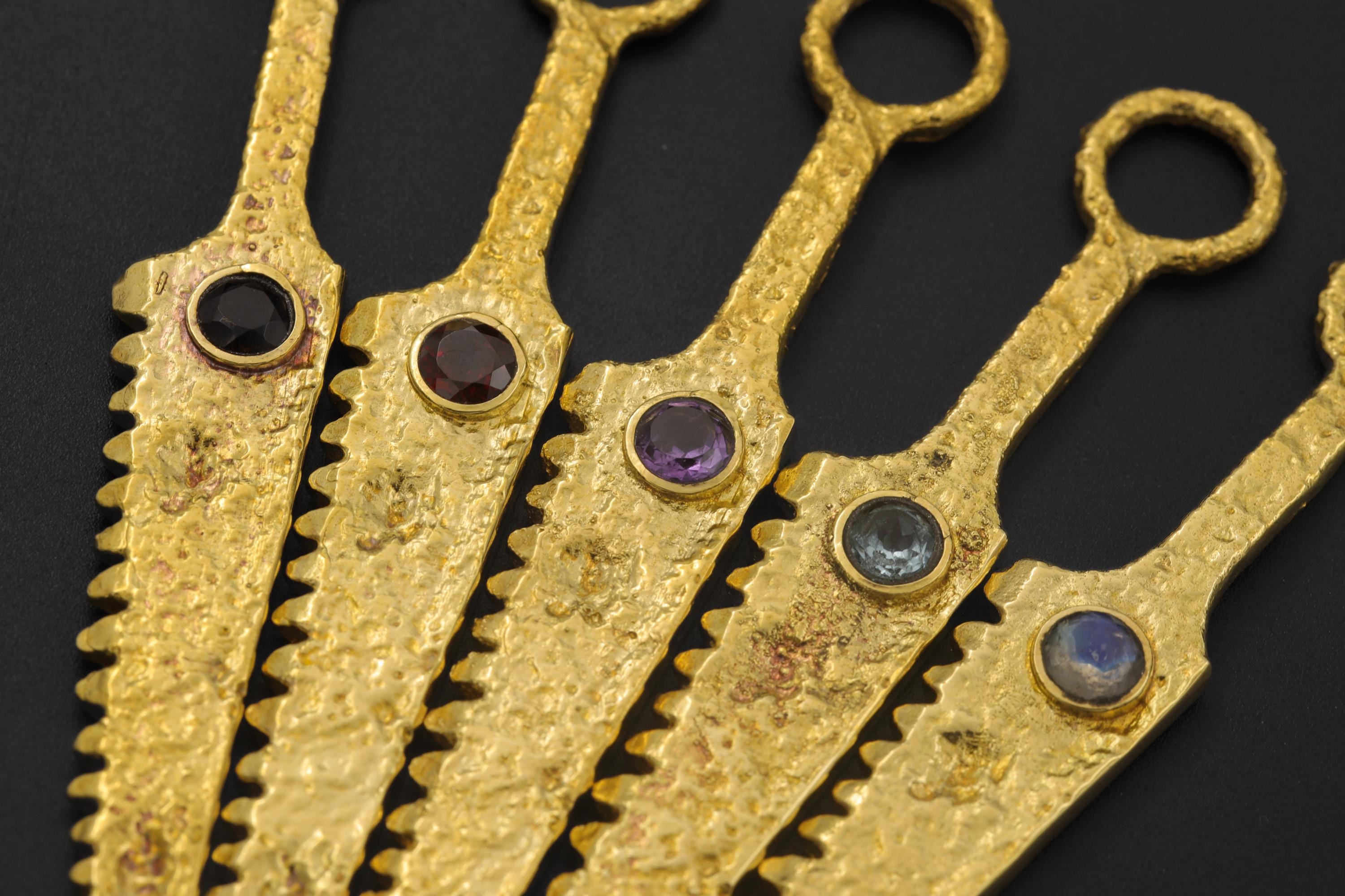 Collection of gold-plated cutter spoon pendants with different gemstone centres displayed together.