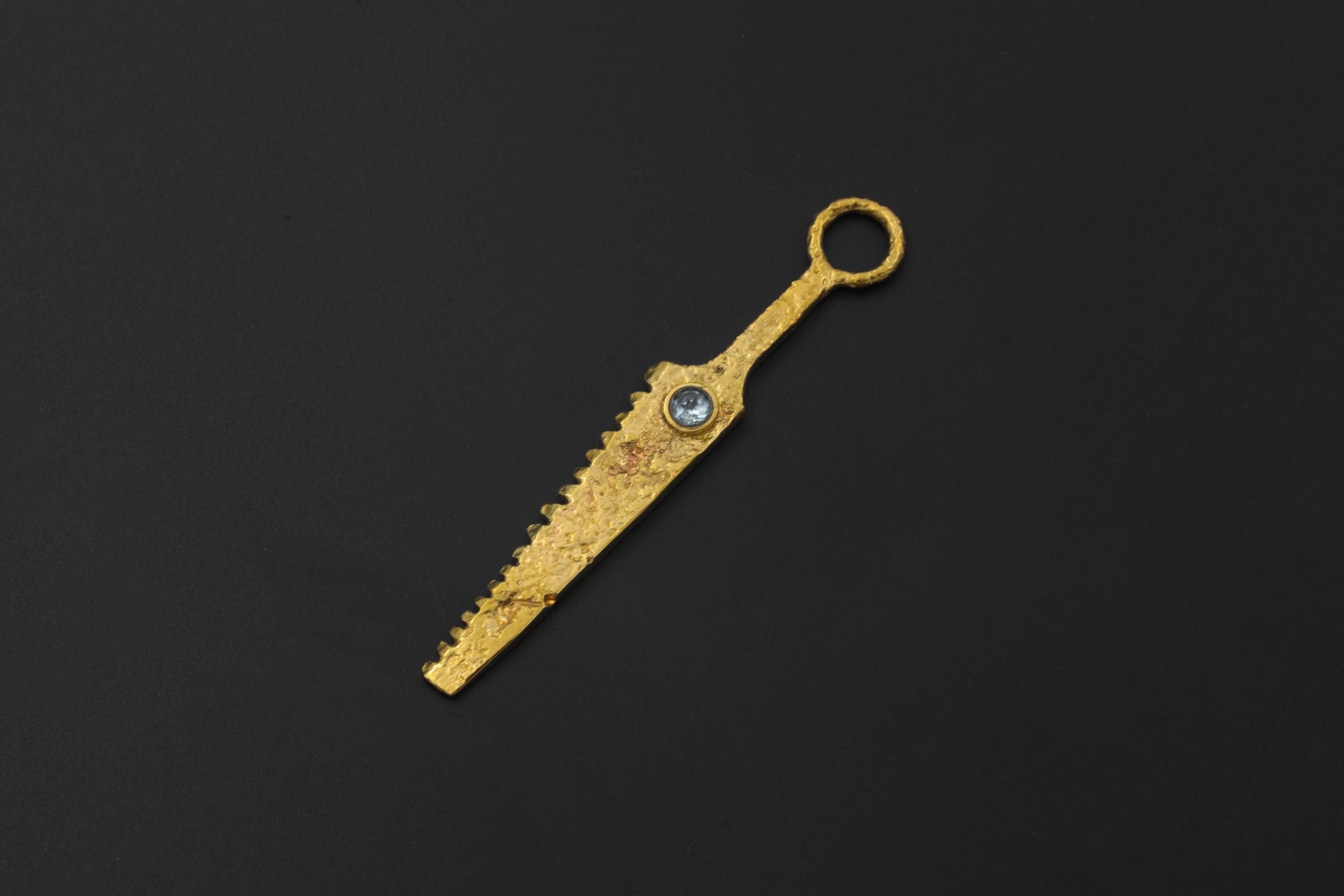 Gold-plated Blue Topaz cutter spoon pendant shown on black background with long serrated form.