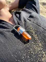 Australian Lemurian Quartz pendant displayed on slate, with orange crystal point and polished hammered sterling silver setting.