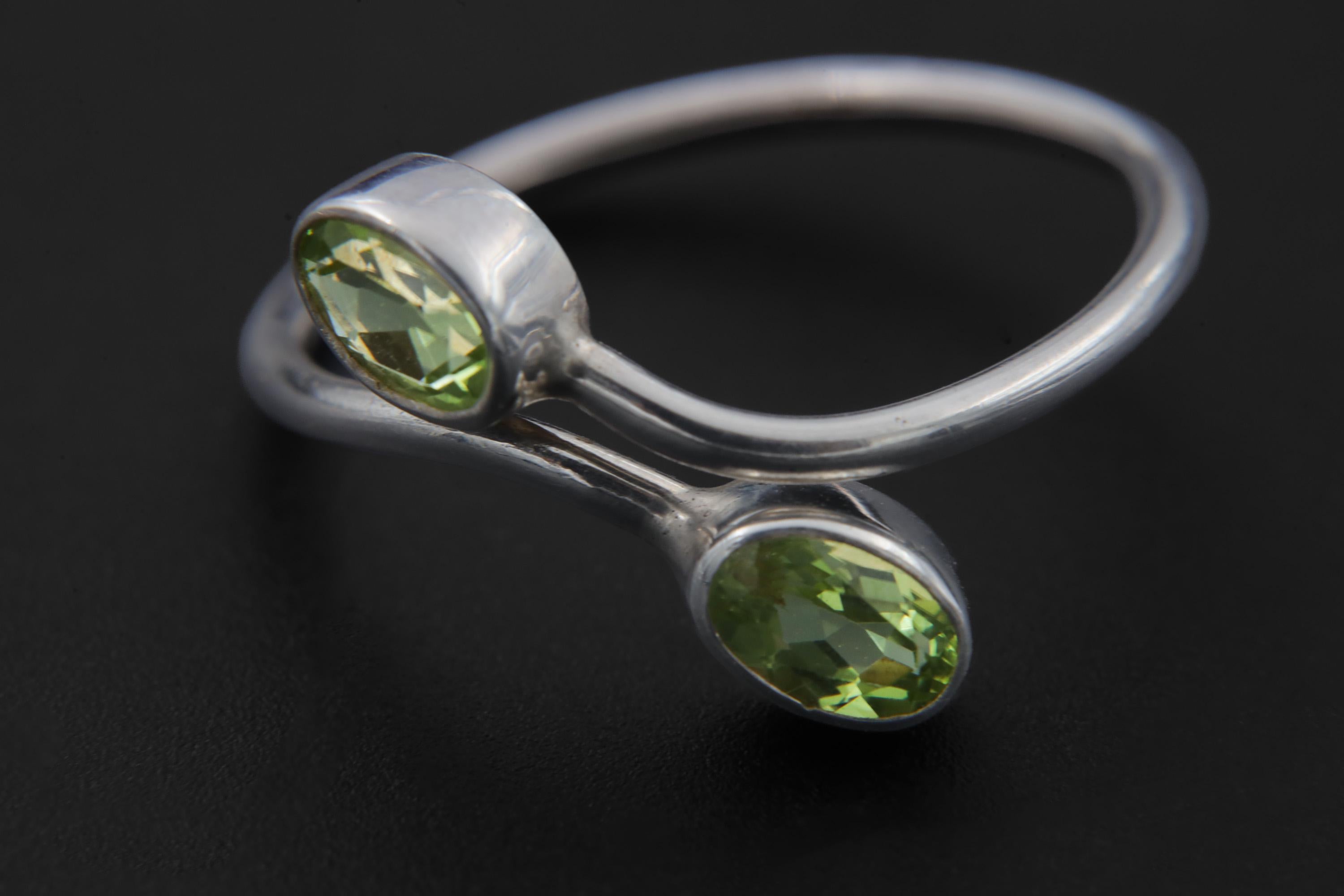 Close view of oval faceted Peridot stones set in polished sterling silver bezels.