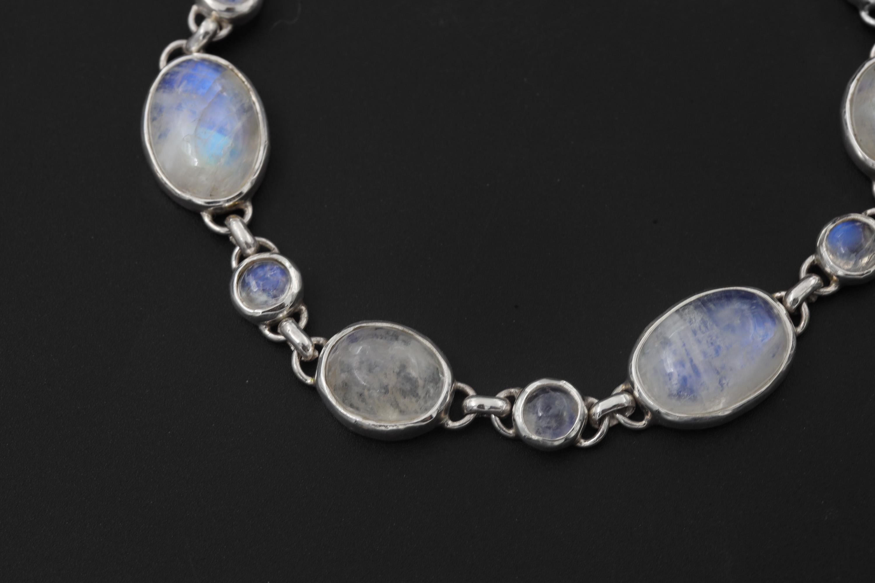Close view of Rainbow Moonstone bracelet showing blue adularescence and linked silver bezel settings.
