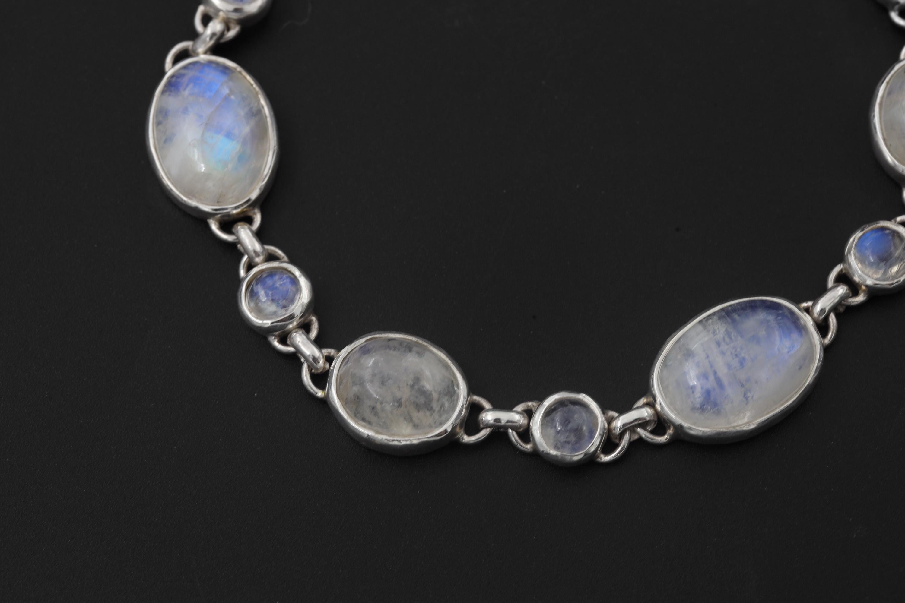 Close view of Rainbow Moonstone bracelet showing blue adularescence and linked silver bezel settings.