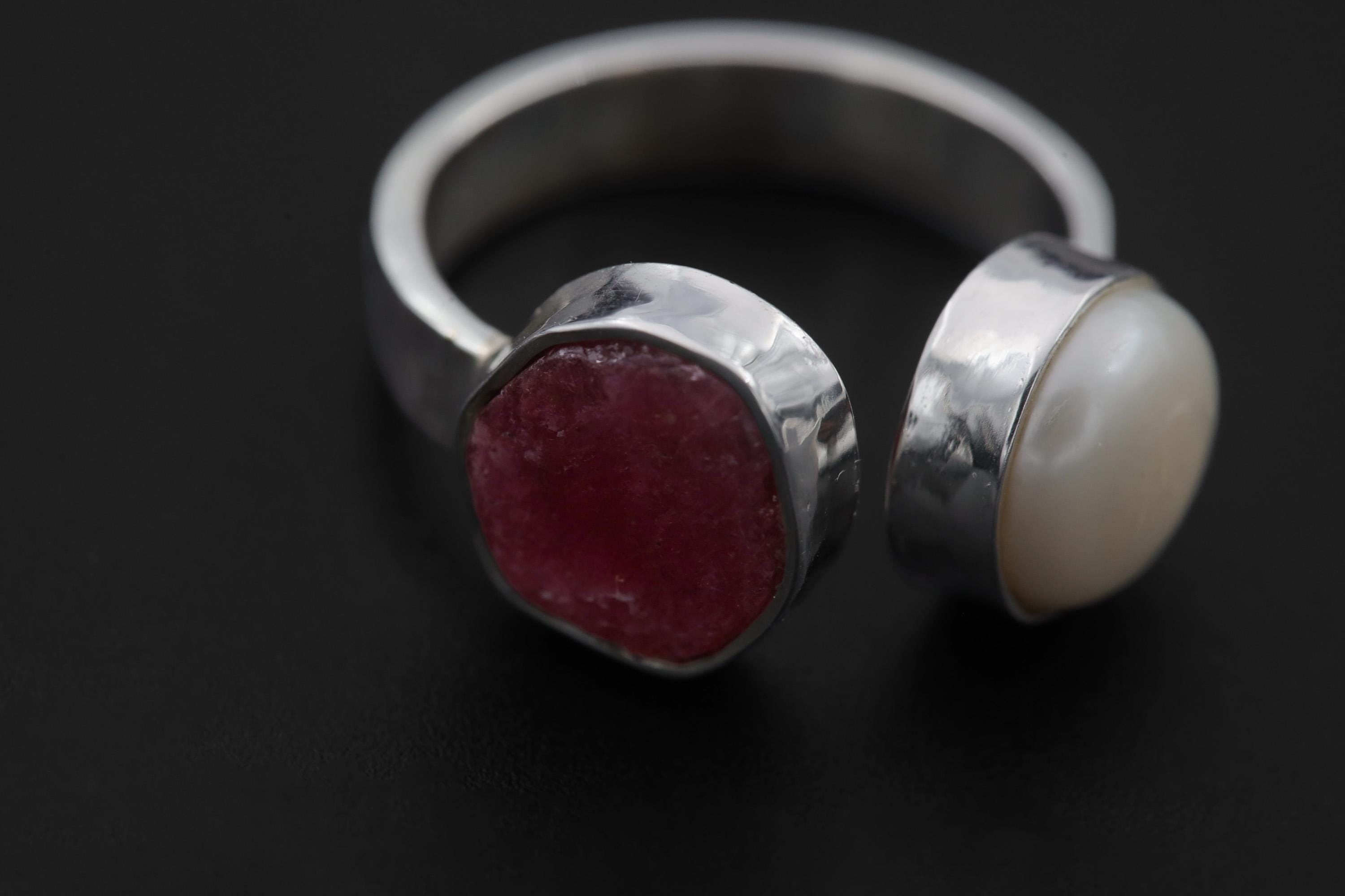 Close-up of natural Ruby cabochon and South Sea Pearl cabochon in bezel-set 925 sterling silver with hammered texture.