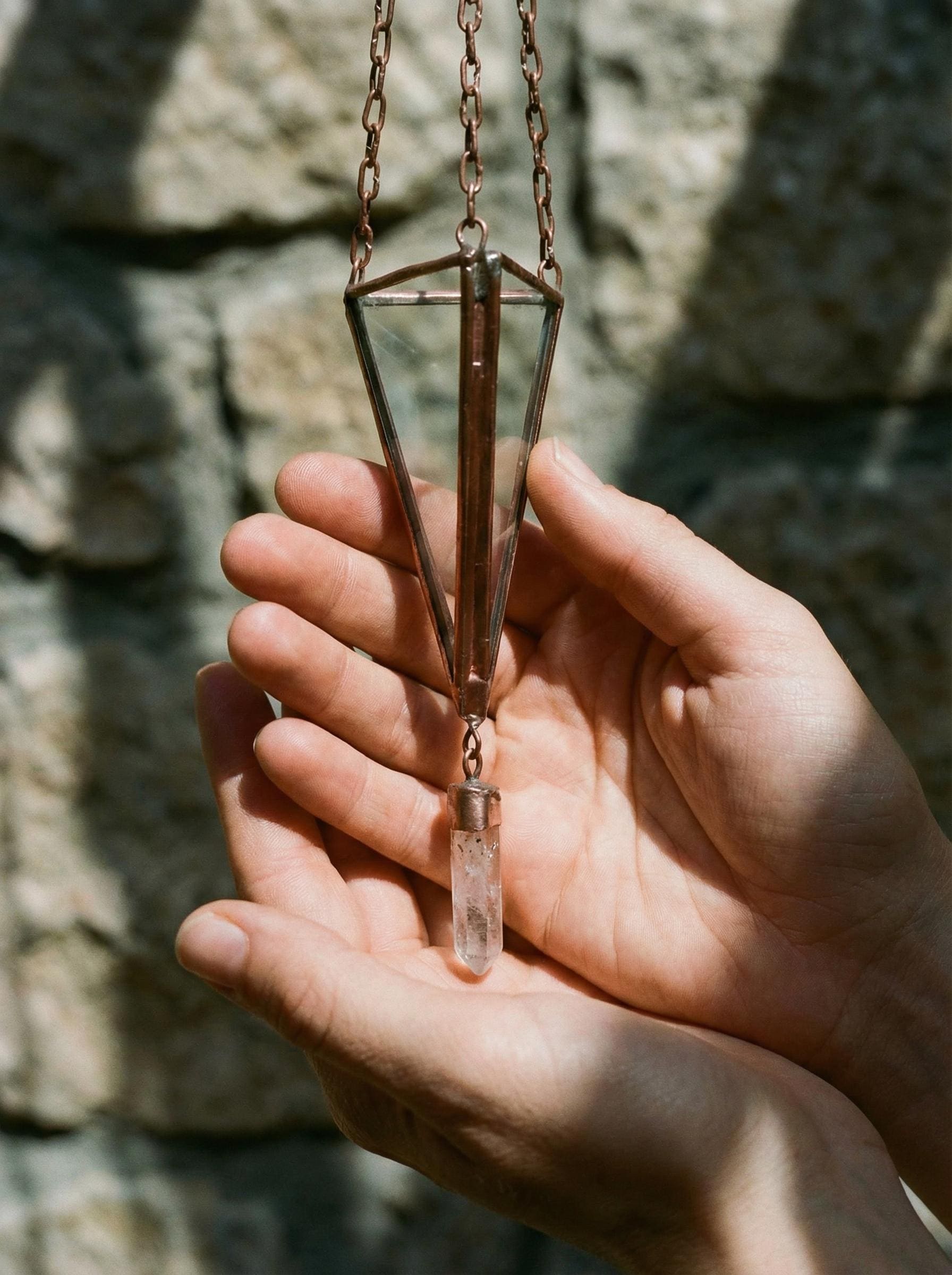 Copper Quartz triangle sun catcher hanging on textured wall with soft natural light and crystal point.