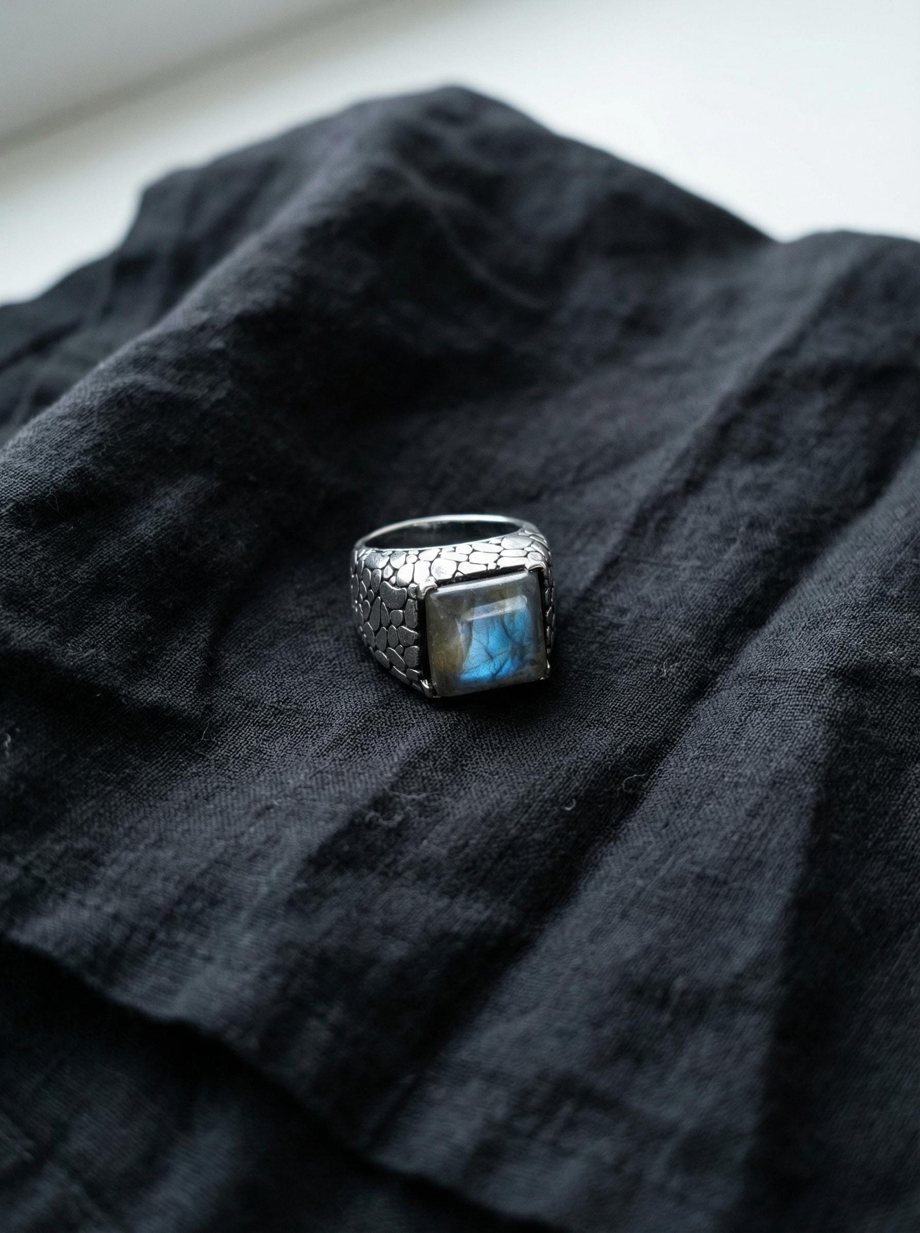 Labradorite ring displayed on stone with textured 925 sterling silver band and glowing blue gemstone.