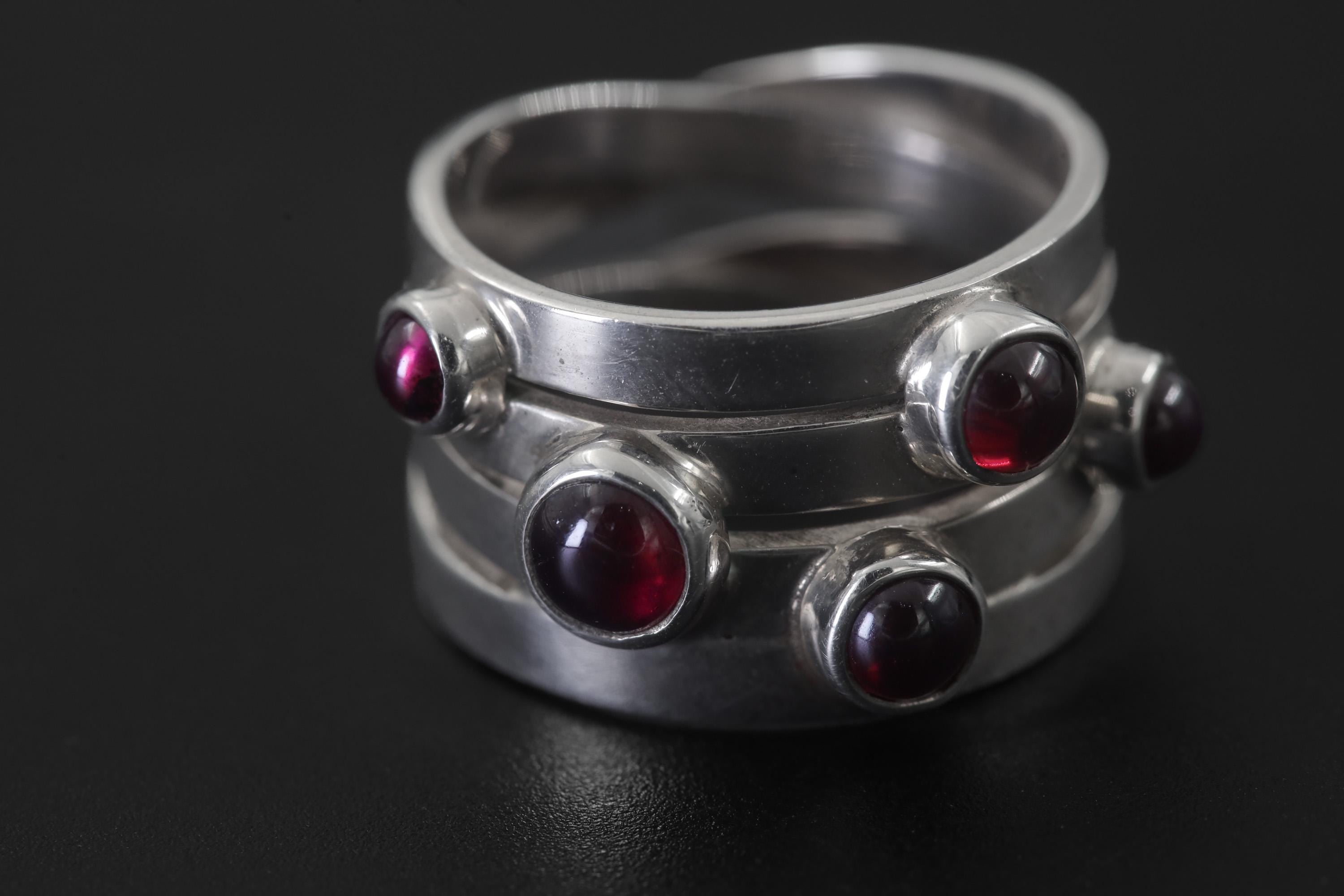 Close view of five Garnet cabochons set in polished sterling silver unity ring.