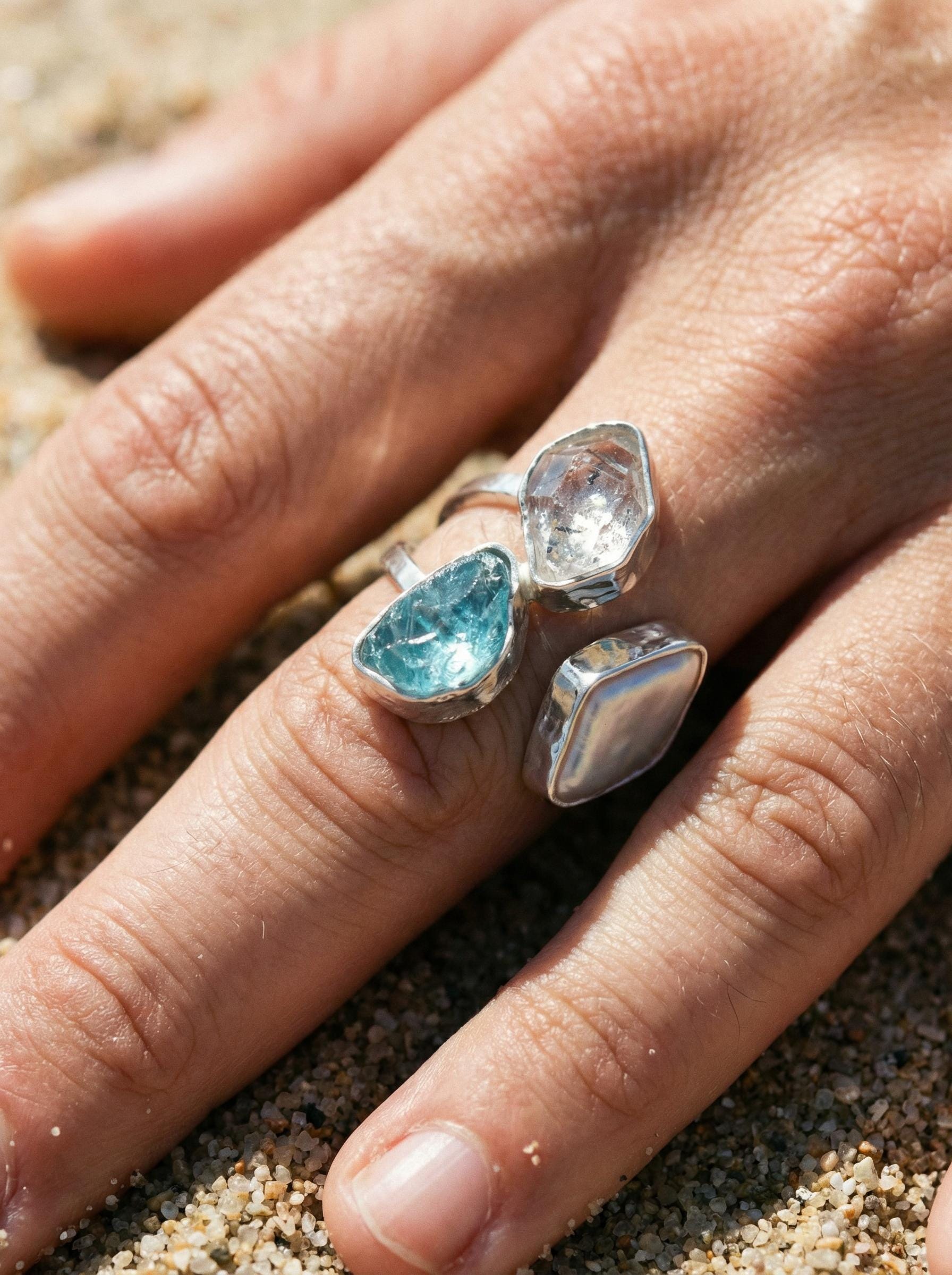 Celestial Tide ring shown worn on the finger, with bright Herkimer Diamond, ocean-blue Apatite, and soft Pearl.