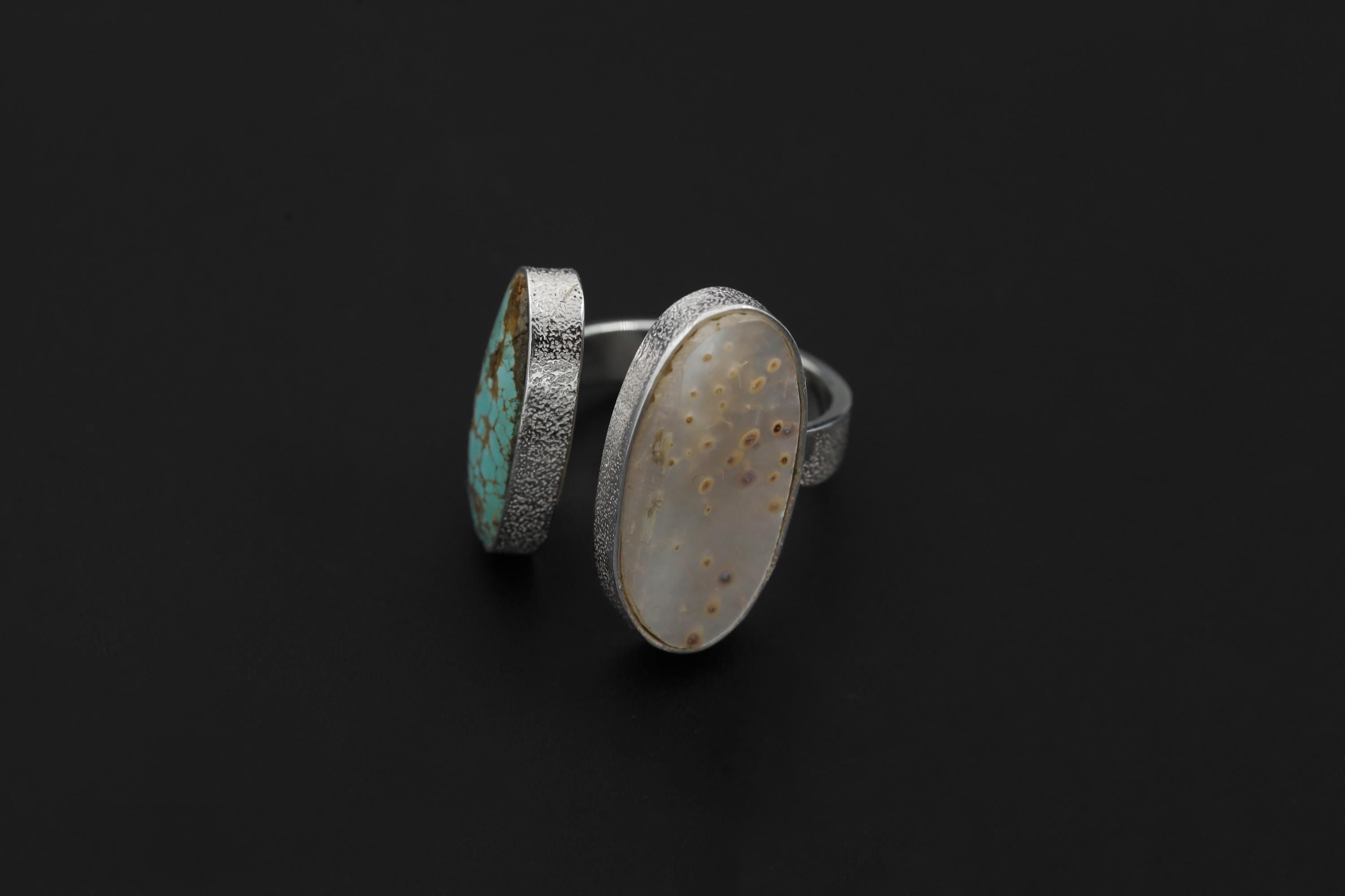 Tide and Shell Mother of Pearl Turquoise ring shown on dark background with opposing bezel-set stones.