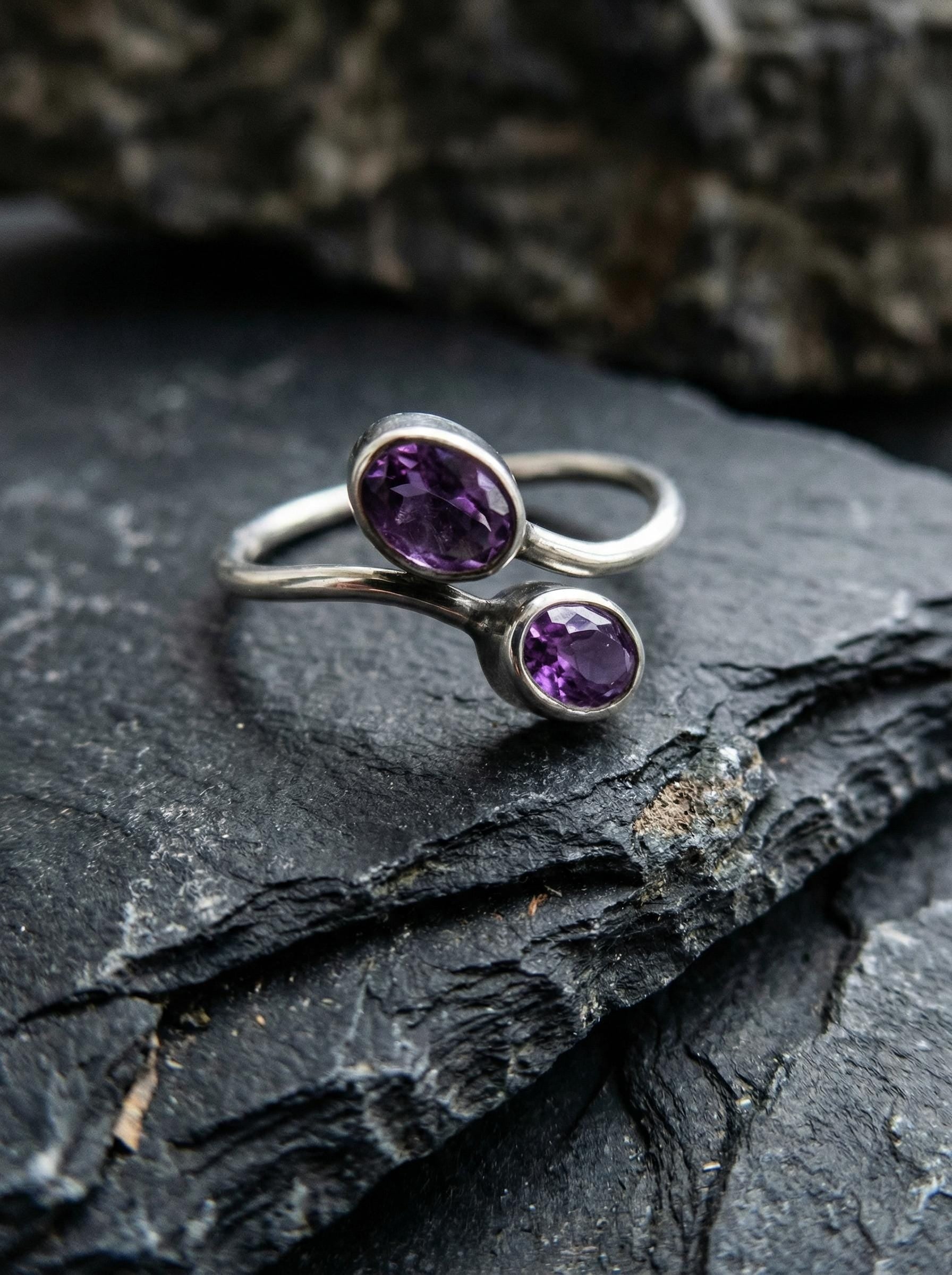 Twin Amethyst open ring displayed on dark slate with polished sterling silver and violet gemstones.