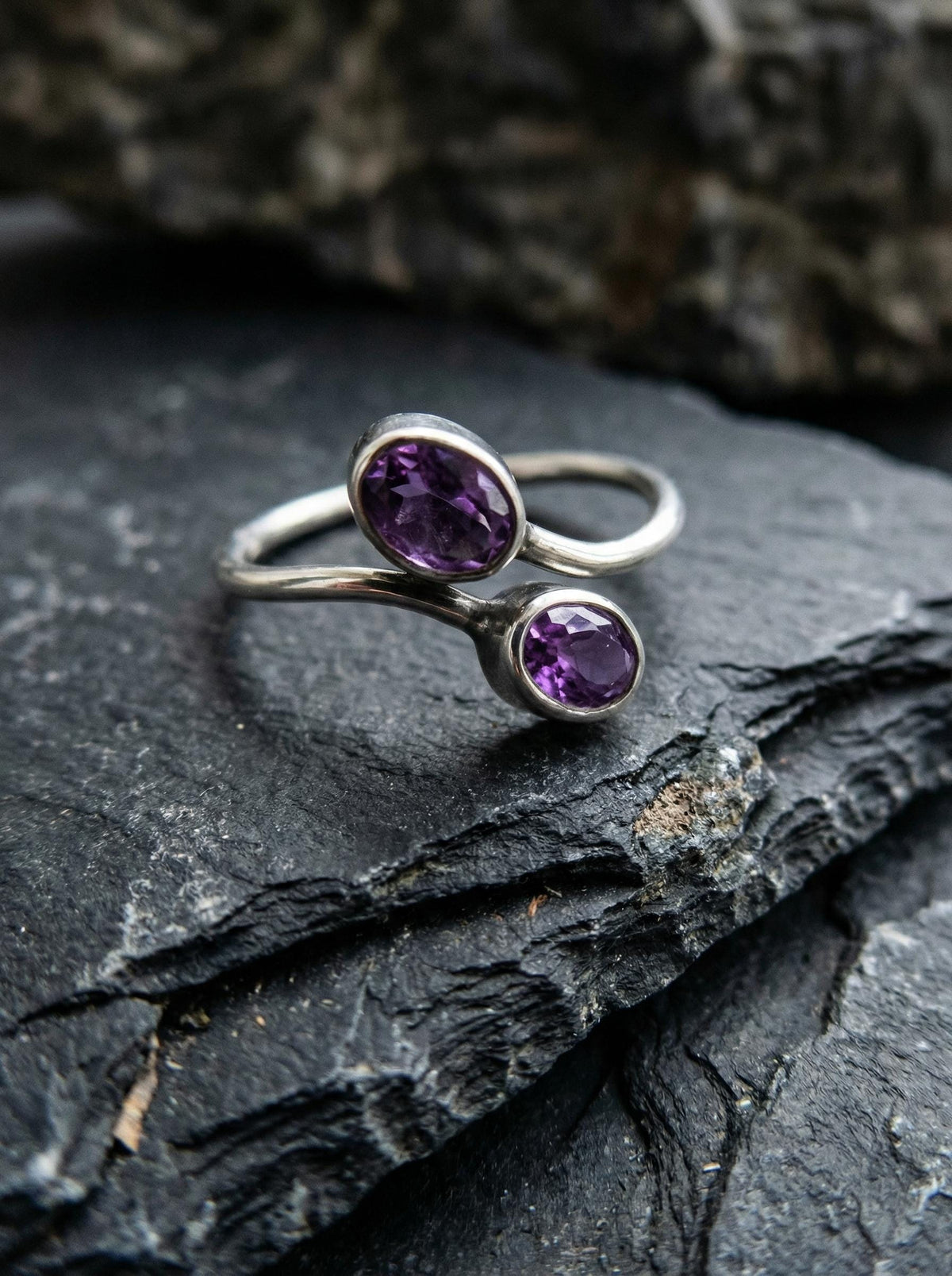Twin Amethyst open ring displayed on dark slate with polished sterling silver and violet gemstones.