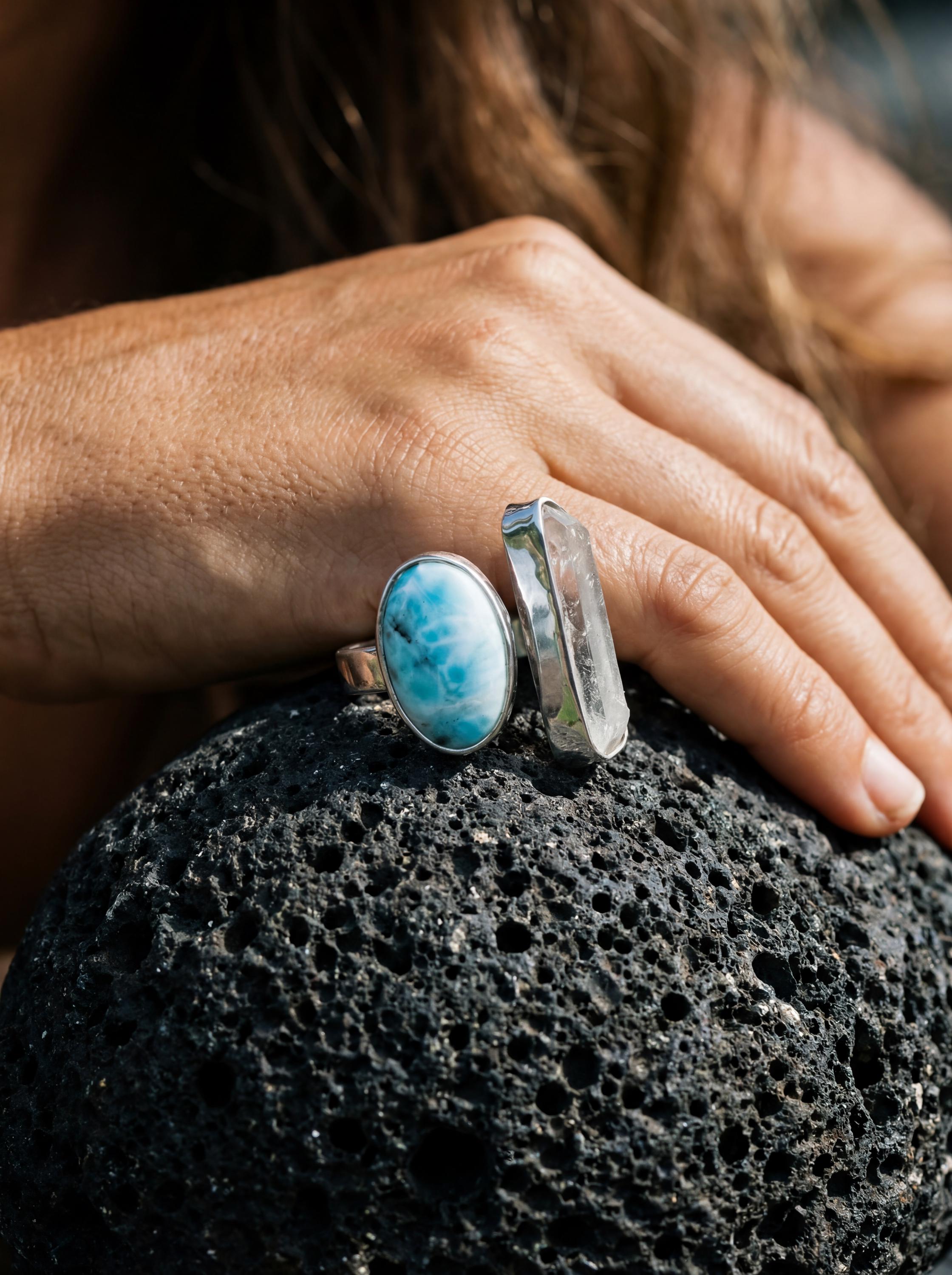 Horizon Flow Quartz and Larimar Ring shown worn on volcanic rock with opposing bezel-set stones and sterling silver band.