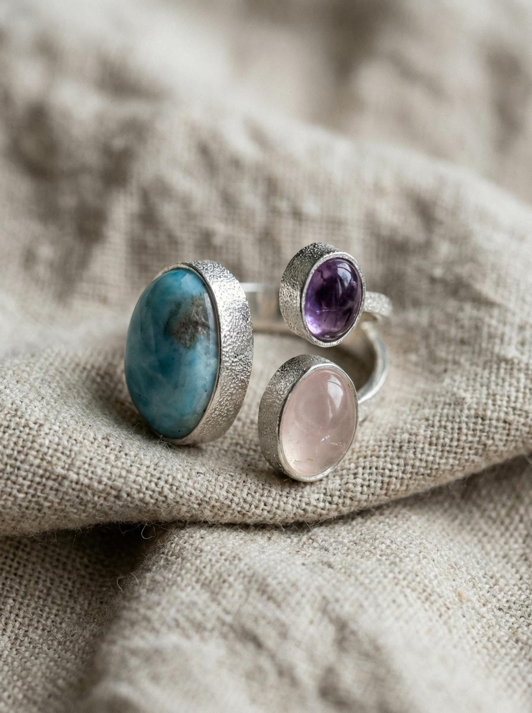 Ocean Heart Multi Stone Ring shown on fabric with blue Larimar, violet Amethyst, pink Rose Quartz, and polished silver.