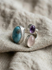 Ocean Heart Multi Stone Ring shown on fabric with blue Larimar, violet Amethyst, pink Rose Quartz, and polished silver.