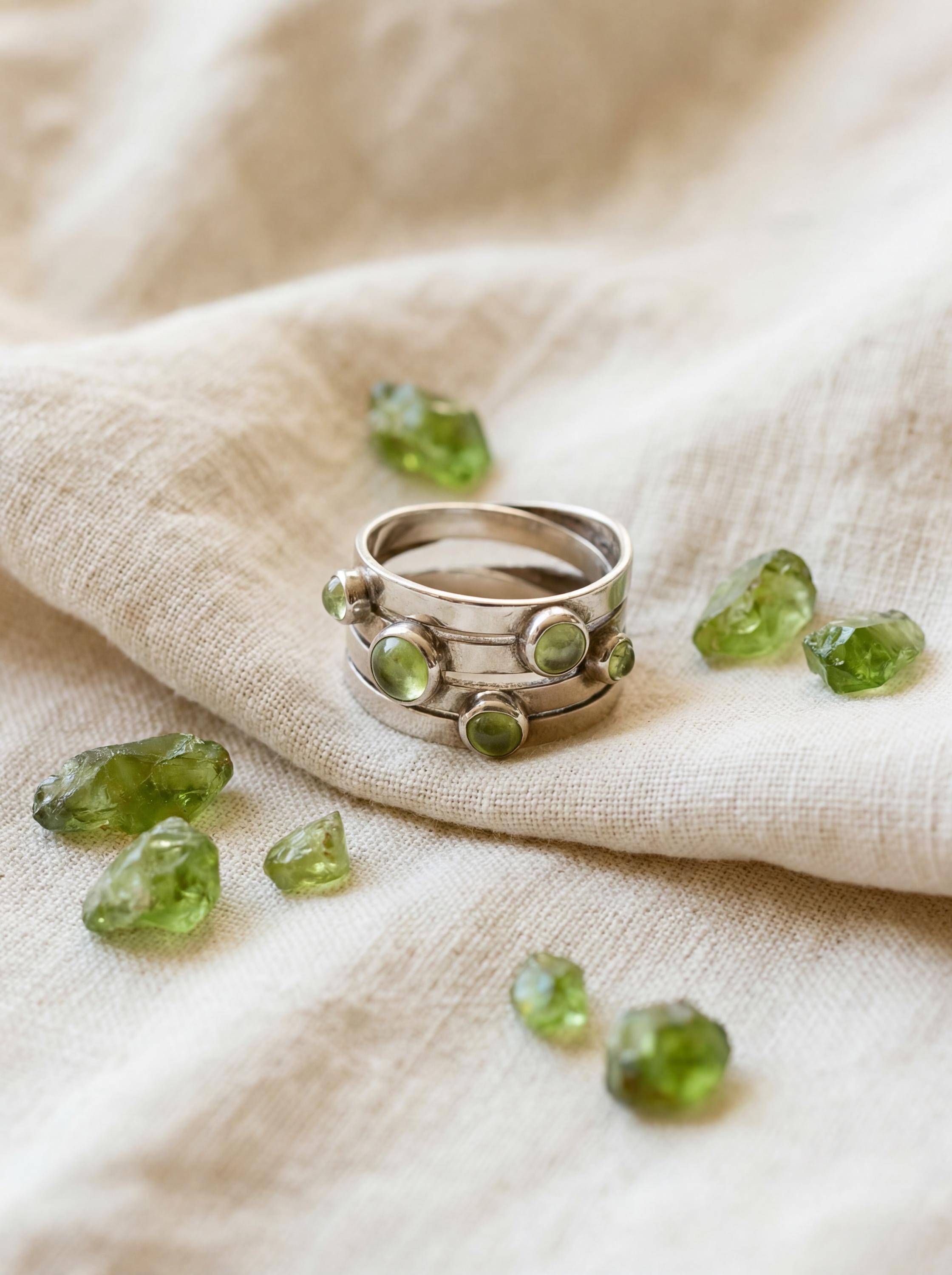 Peridot Orbit Ring displayed on fabric with green gemstones and handmade sterling silver band.