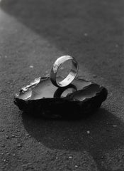 Hammered sterling silver band shown on dark stone with polished handmade texture.