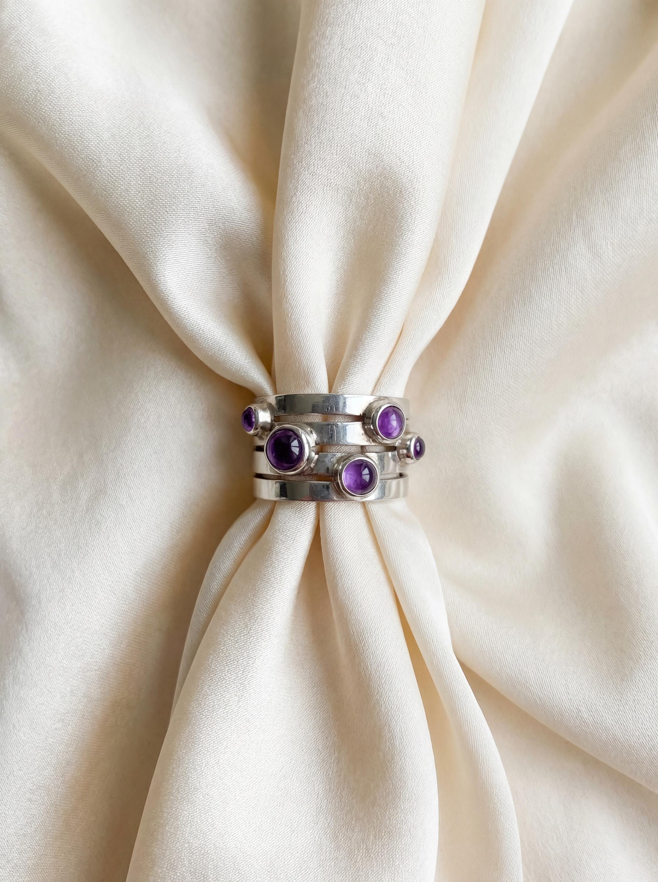 Amethyst Unity Ring displayed on soft fabric as a sculptural five stone sterling silver ring.