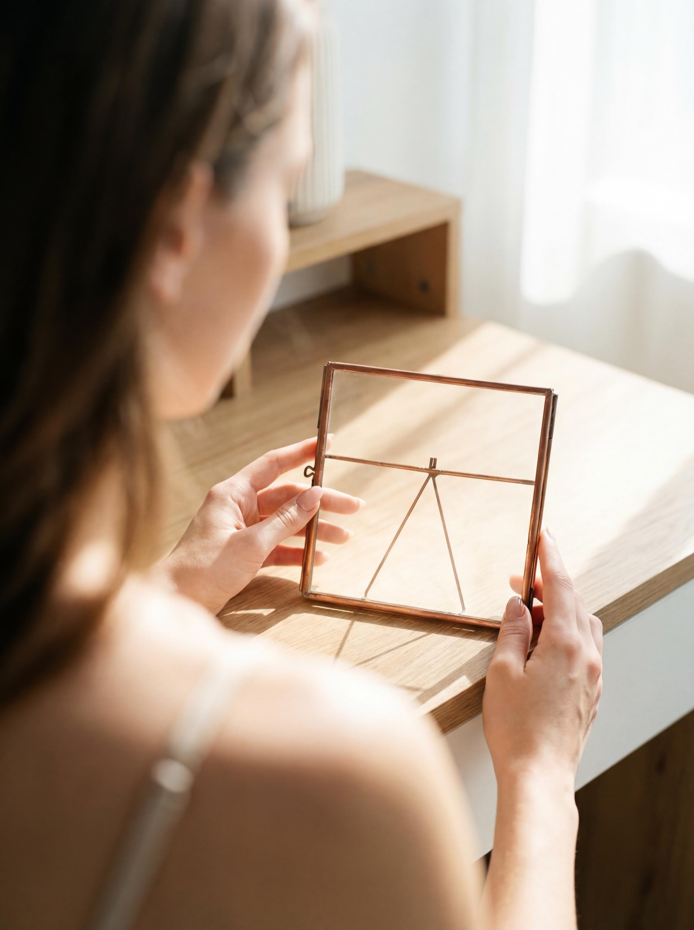 Handmade copper photo frame shown near a window, highlighting clear glass panels and minimal square design.