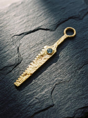 Gold-plated Blue Moonstone cutter spoon pendant displayed on slate as a functional ritual talisman.