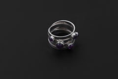 Five stone Amethyst ring displayed on dark background showing solid polished silver band.