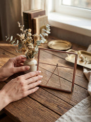 Handmade copper and glass photo frame styled on a wooden table with flowers and warm natural light.