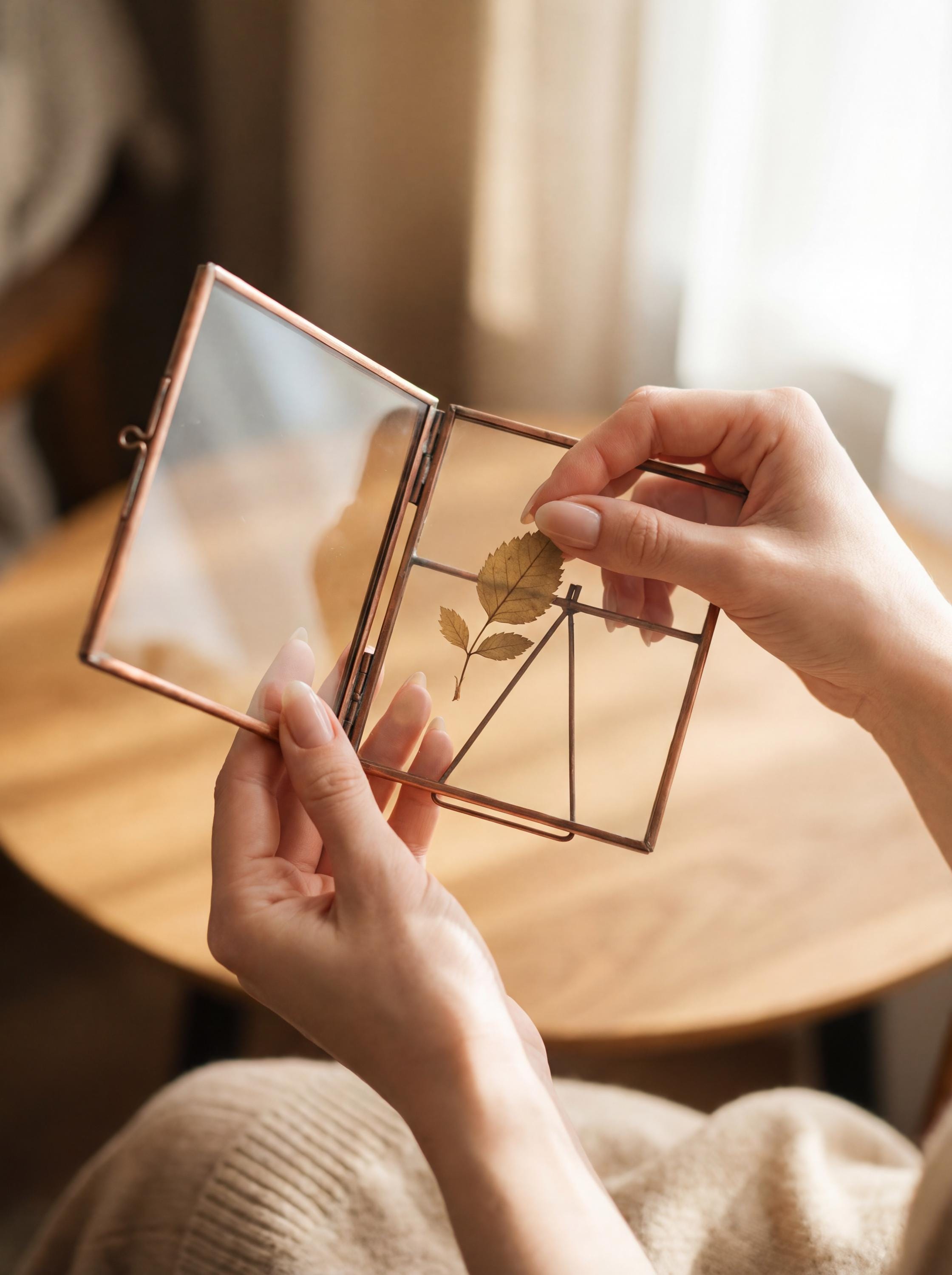 Copper glass photo frame opened and held near a table, showing how keepsakes or small photos can be placed inside.